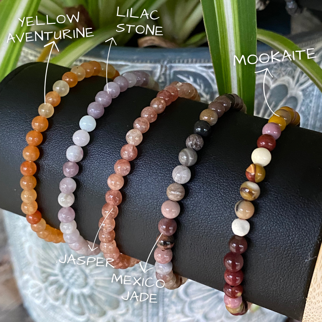 a display stand showing three different stacking stretch bracelets made with 4mm yellow aventurine, Lilac Stone, jasper, Mexico jade and Mookaite