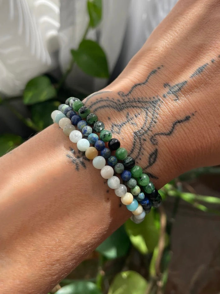 A wrist shot showing three different stacking stretch bracelets made with 4mm Sodalite, Labradorite, and Moss Agate stones.
