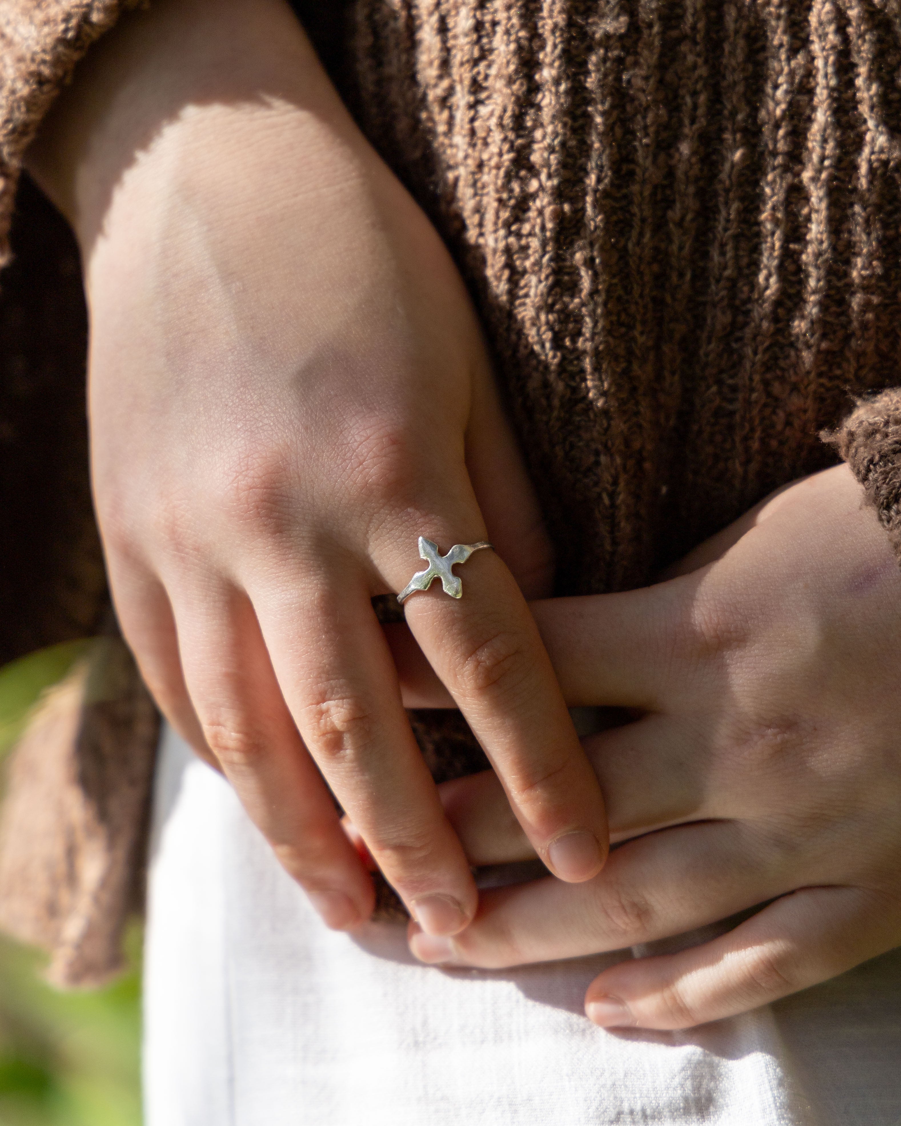 Close-up of hands with a silver ring featuring a flower design.