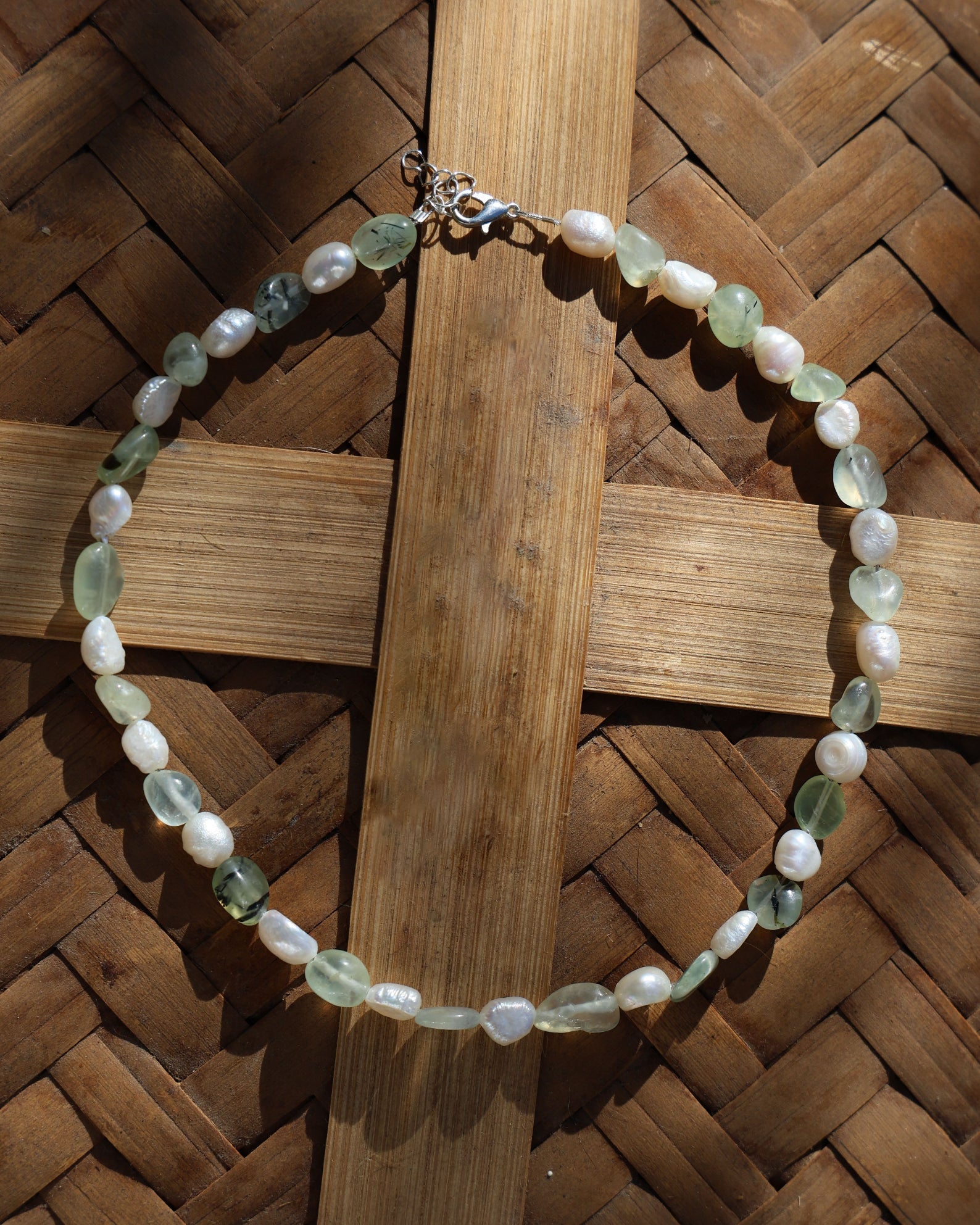 Necklace with green and white beads on a woven wooden surface