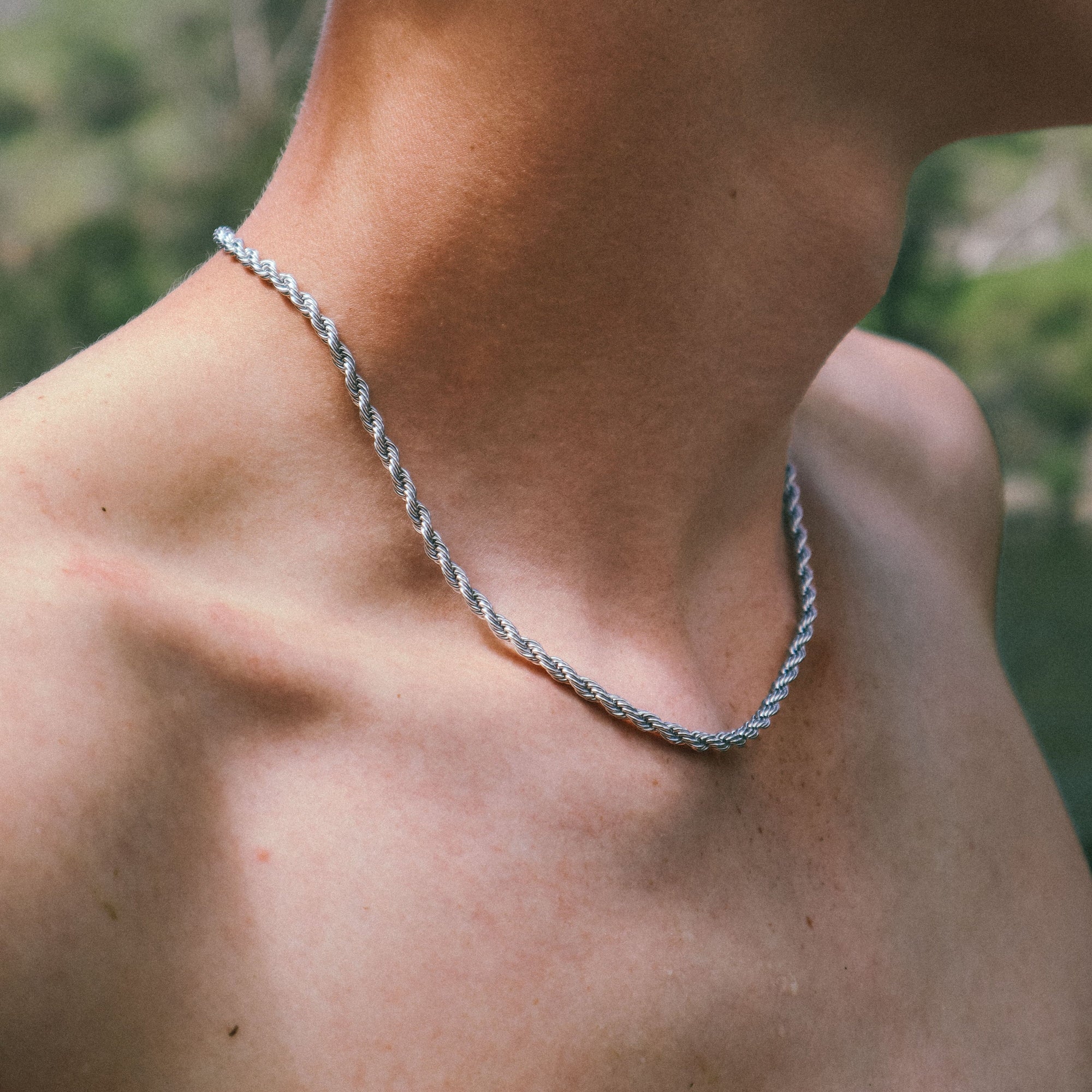 Close-up of a silver bracelet on a wrist with a blurred natural background