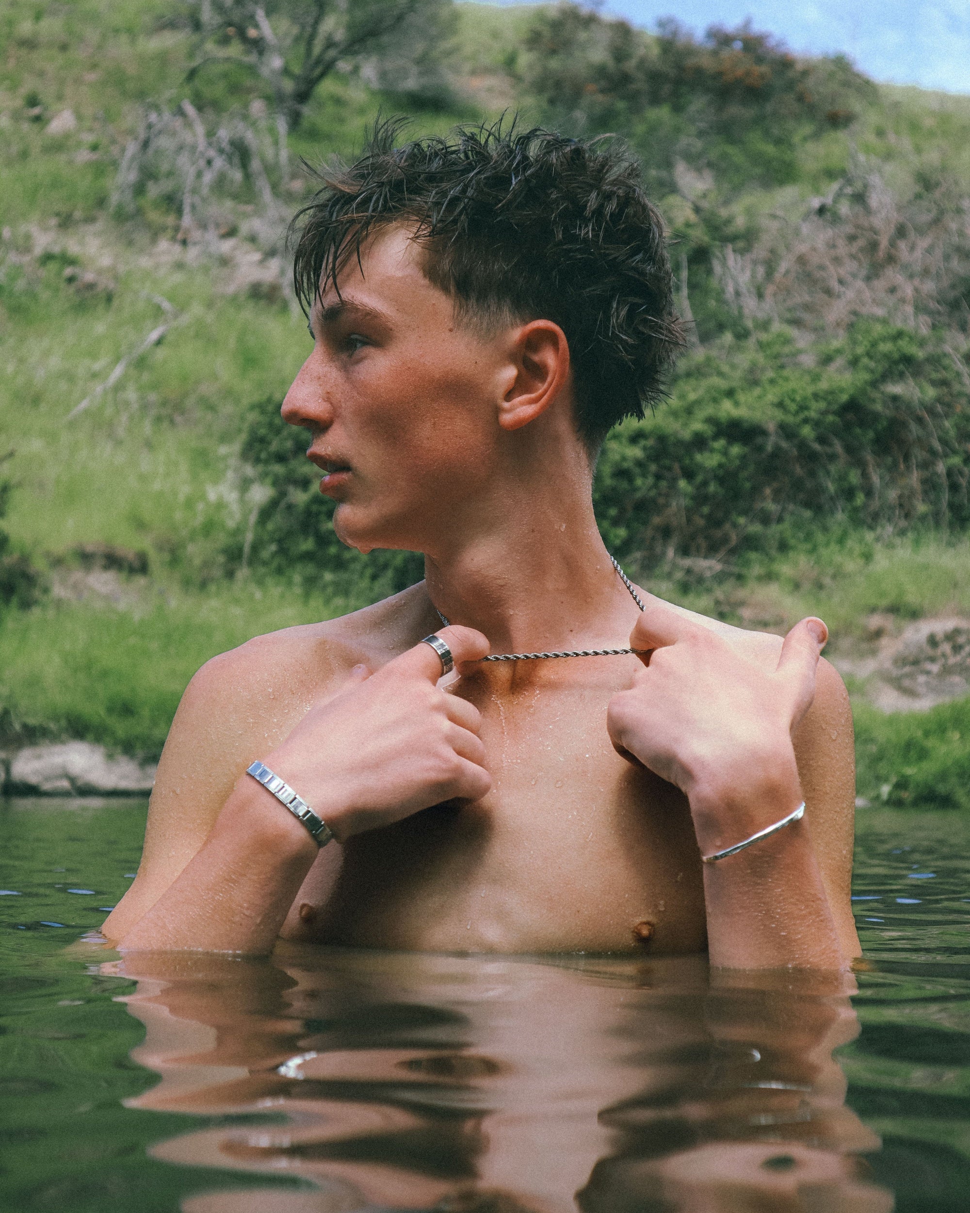 Man standing in a natural setting with water reflection