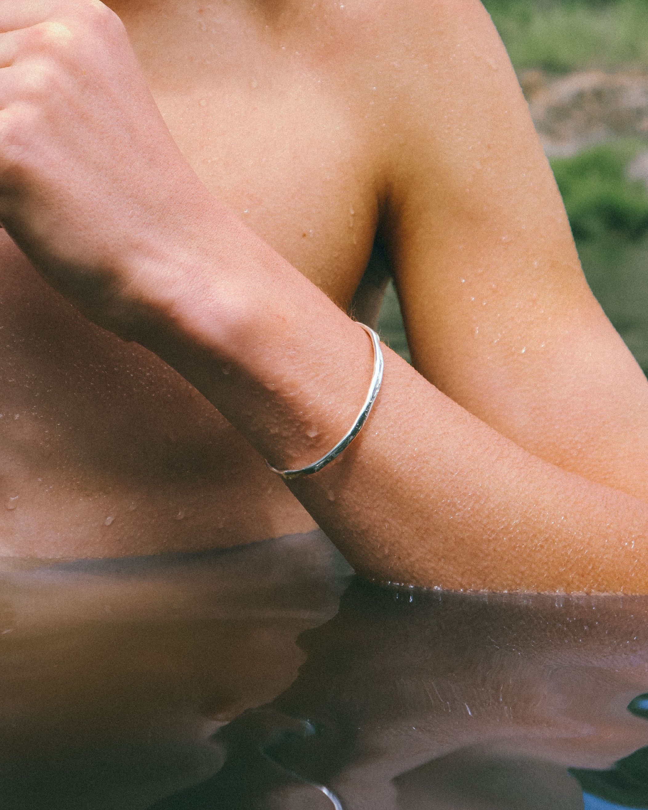 Close-up of a person's arm with a silver bracelet, blurred background