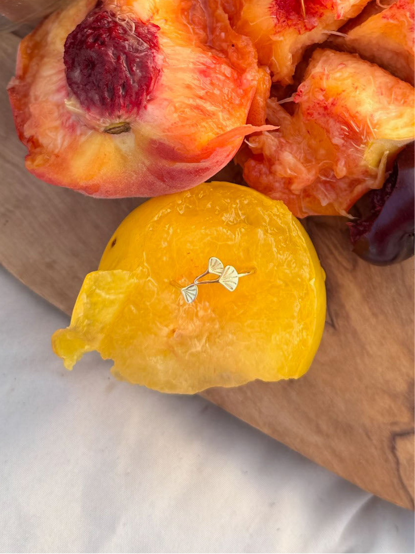 ginkgo ring placed in peaches on a wooden cutting board with a yellow fruit.