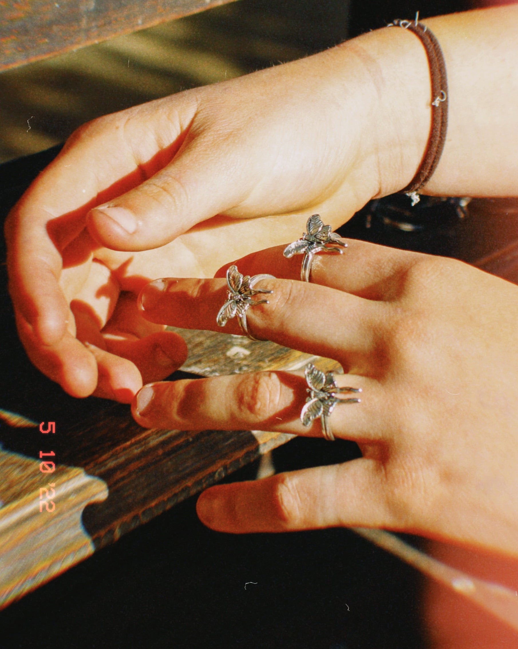 Close-up of hands wearing silver rings with a blurred background