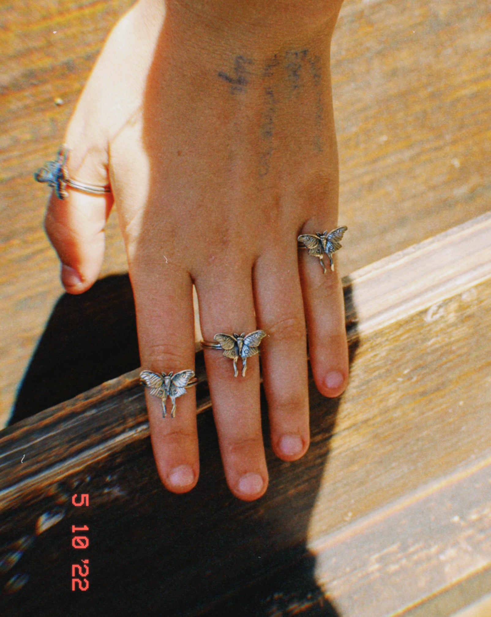 Hand with multiple rings on a wooden surface