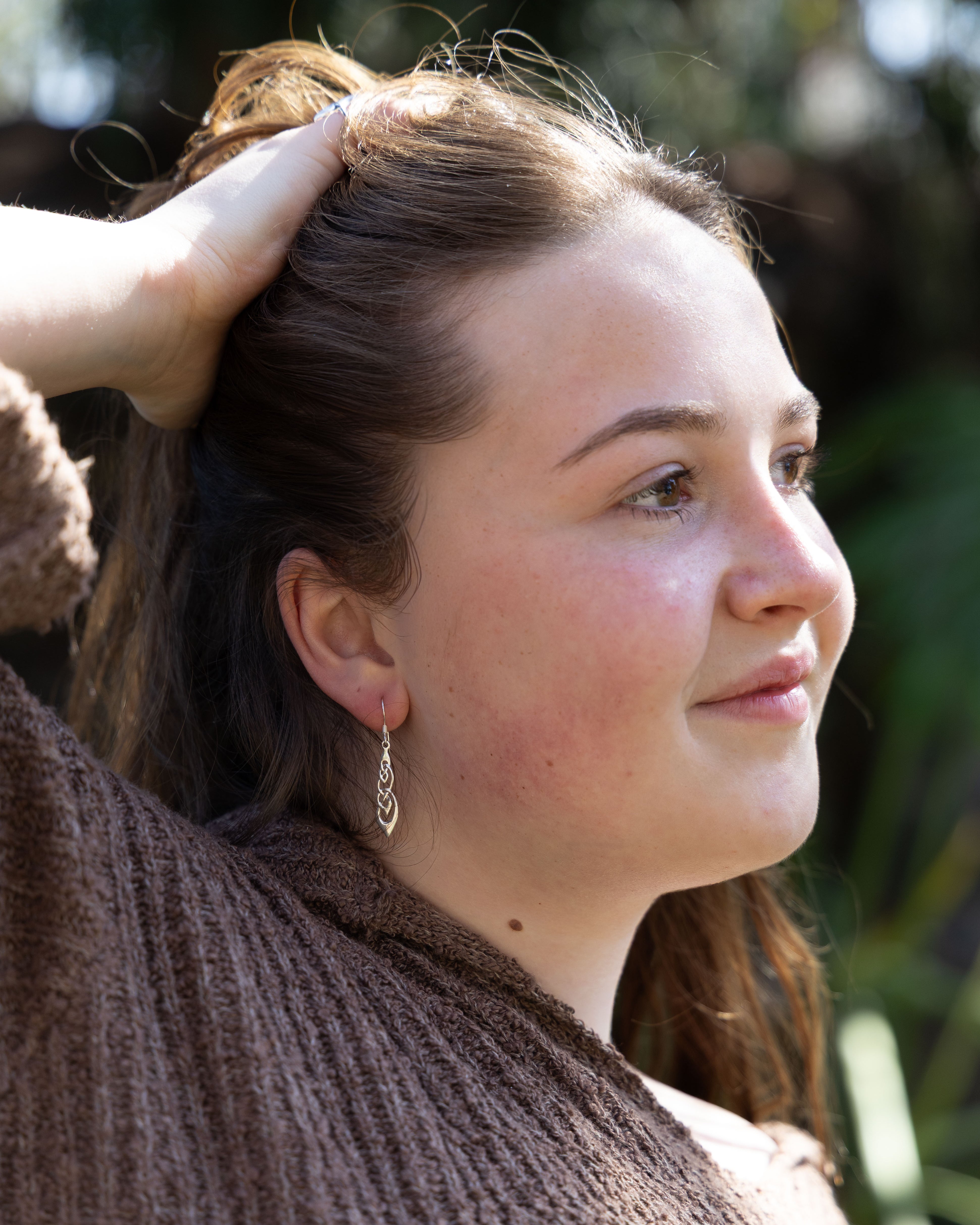 Woman with a delicate earring looking downwards with a blurred background