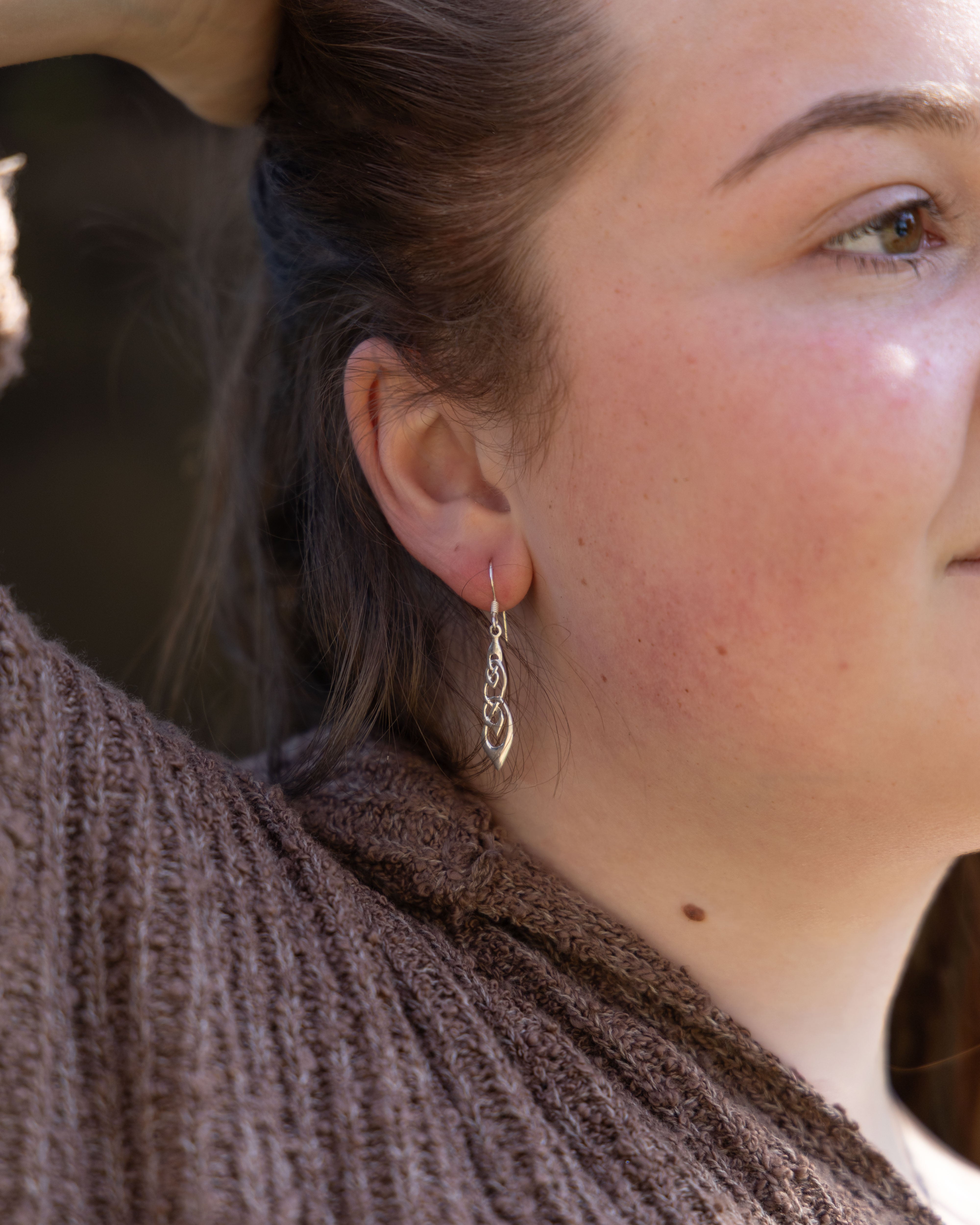 Close-up of a person wearing a silver earring with a blurred background