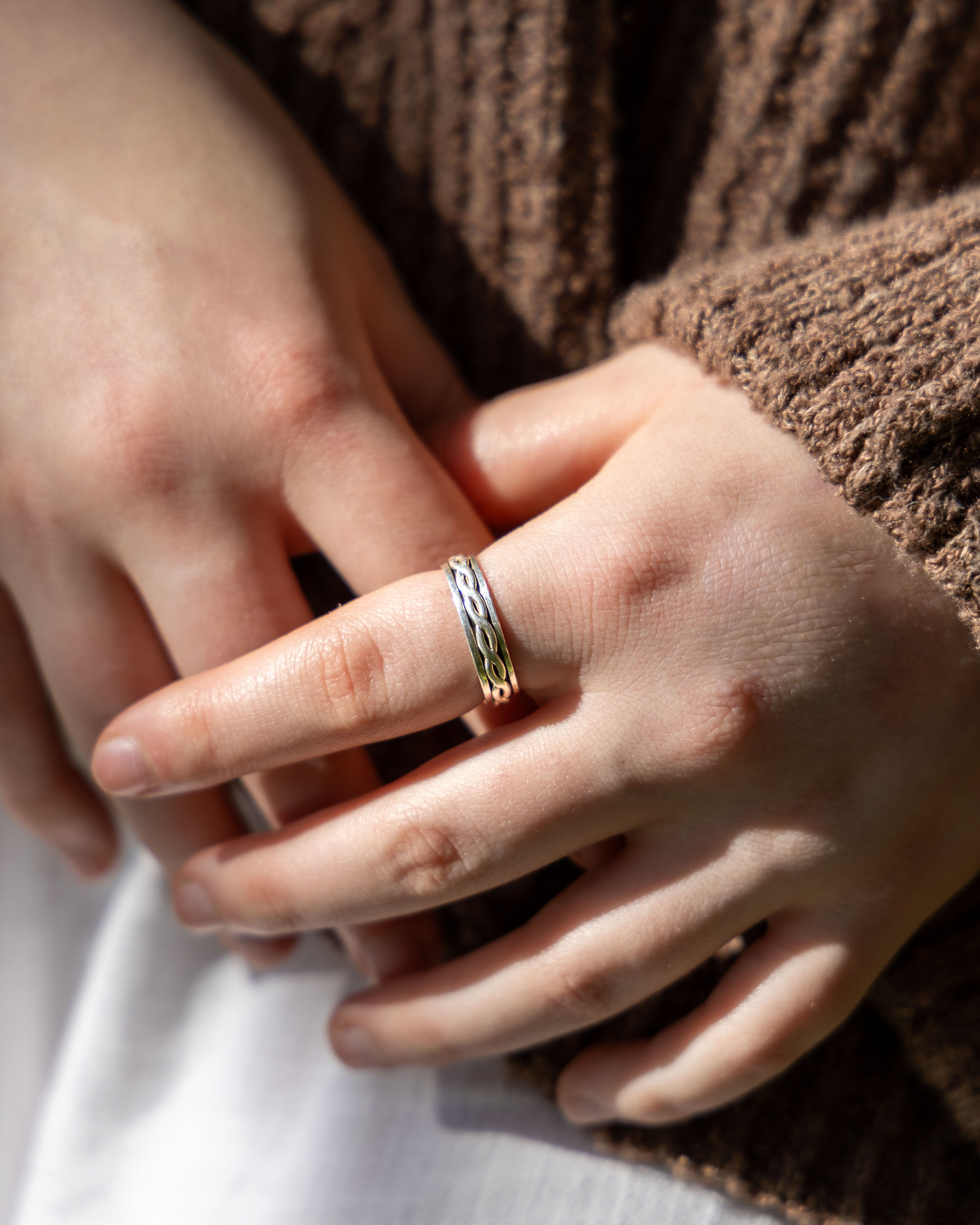 Close-up of a hand wearing a silver ring with a textured band.