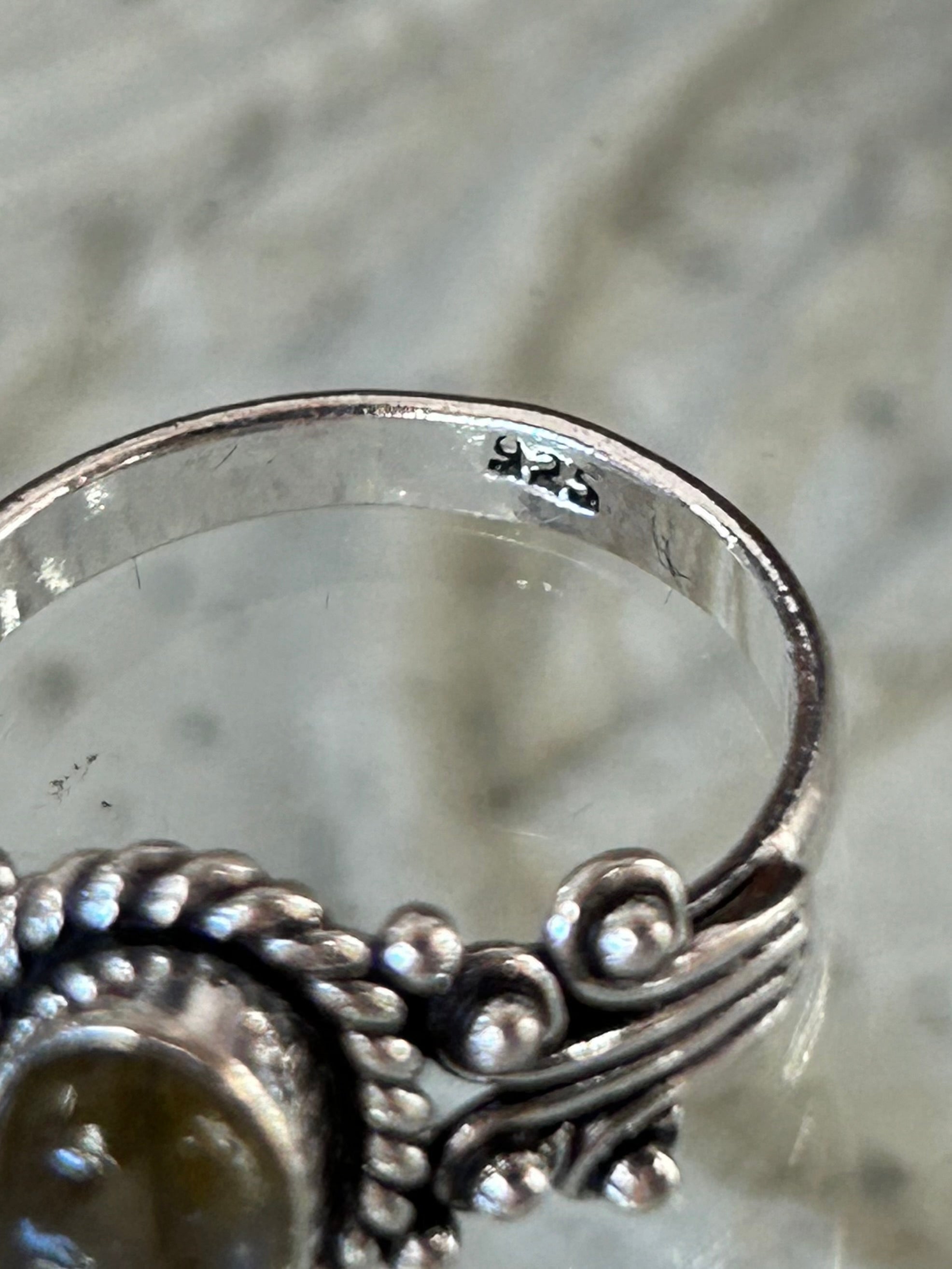 A silver ring with a labradorite stone, featuring intricate detailing. showing 925 stamp