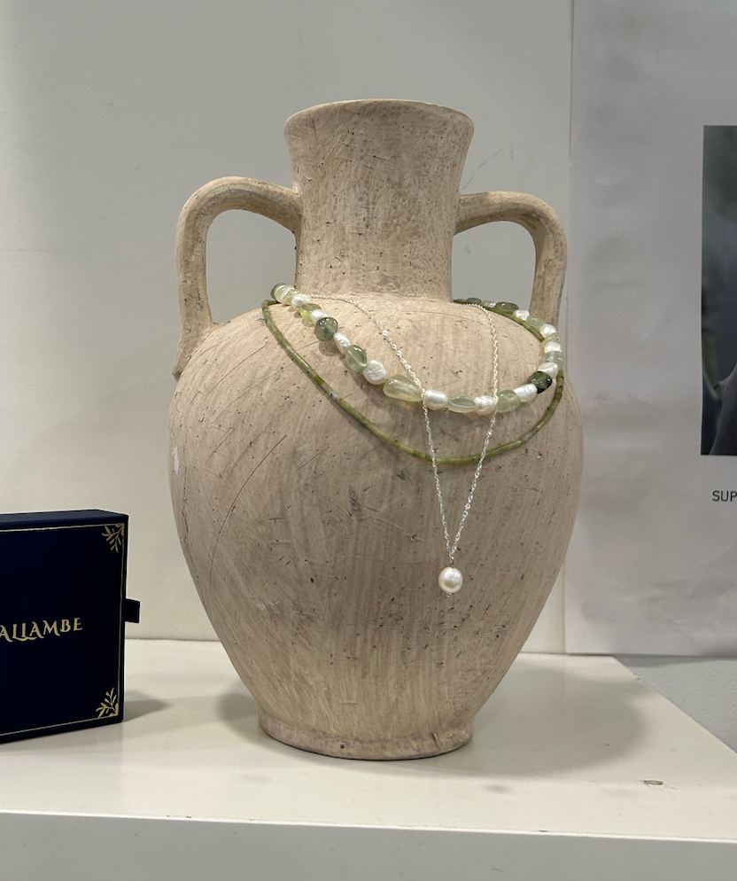 Decorative necklace on a textured vase with a plain background