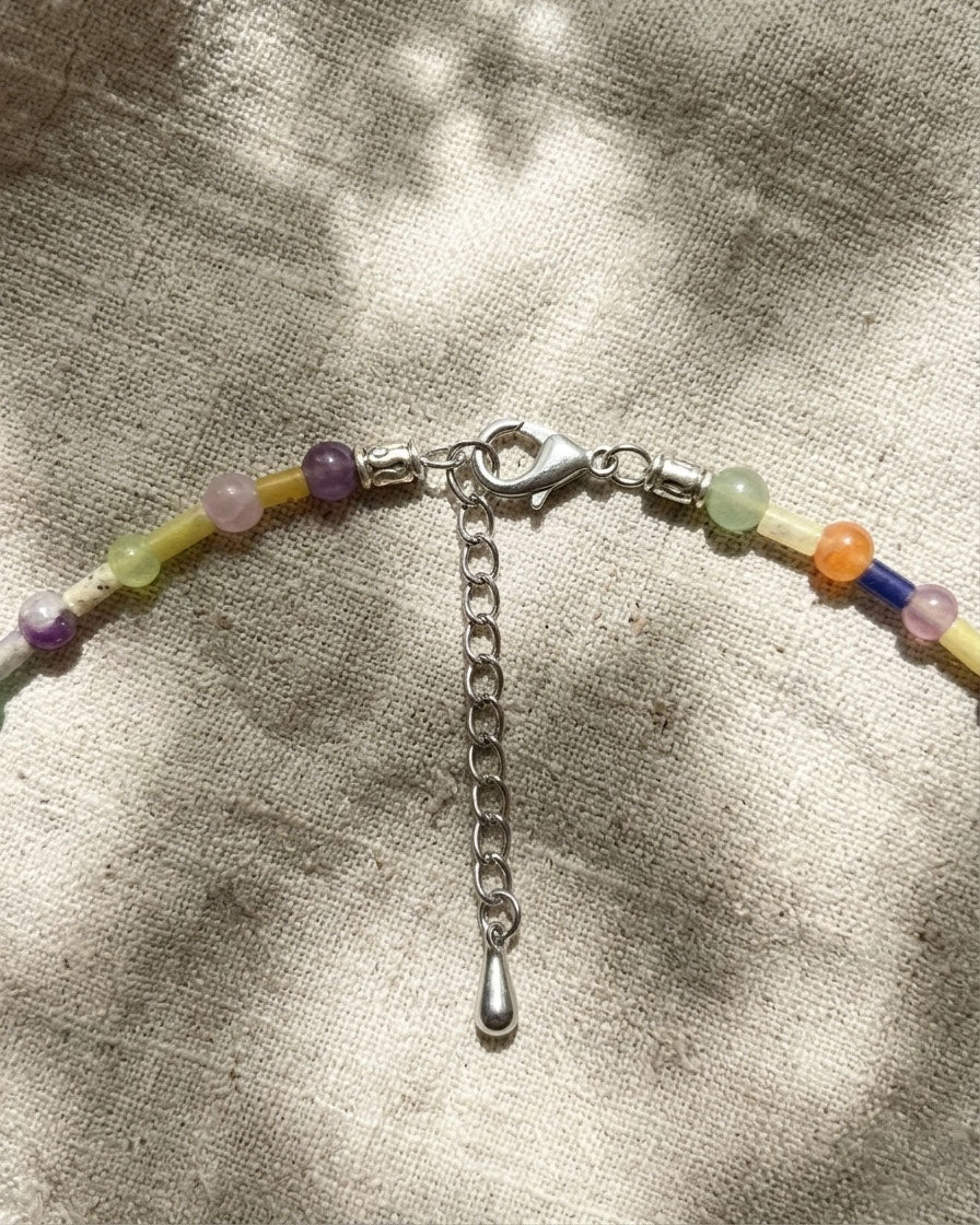 Colourful beaded necklace with a silver clasp on a textured fabric background