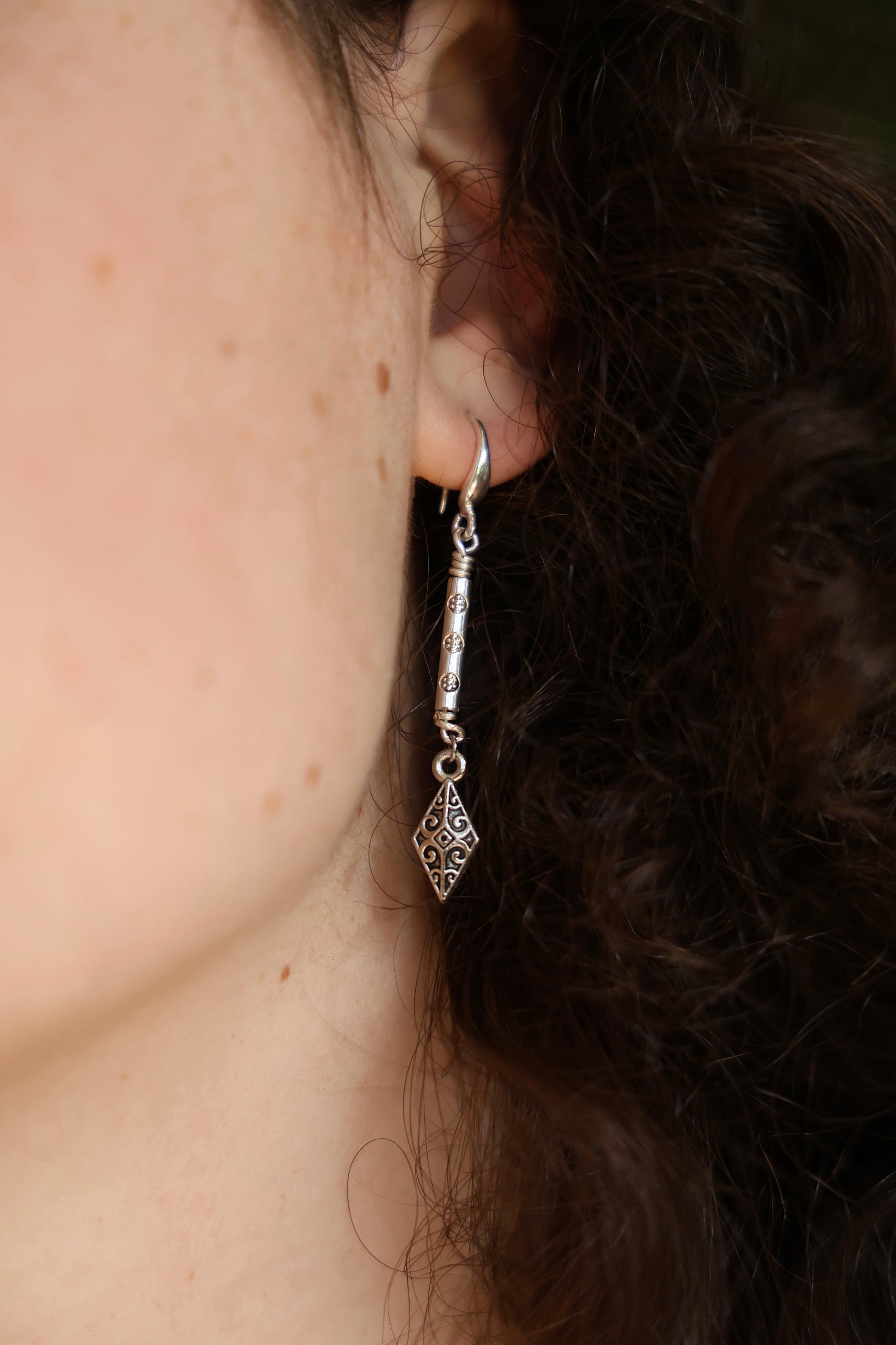 Close-up of a person wearing a silver earring with intricate design.