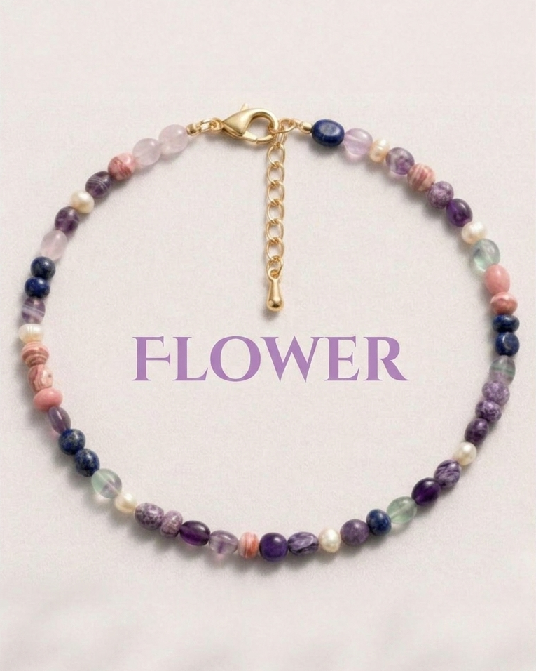 Multicolored beaded bracelet with a gold clasp on a light pink background, featuring the word 'FLOWER'.