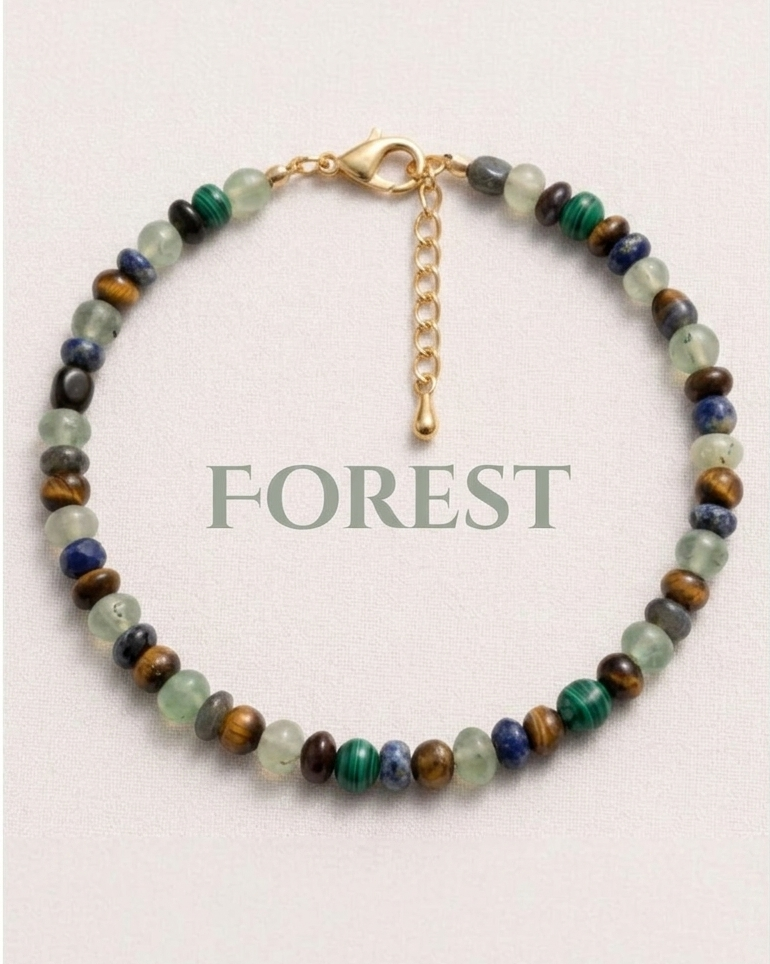 Beaded bracelet with gold chain on a light pink background, labeled 'FOREST'.