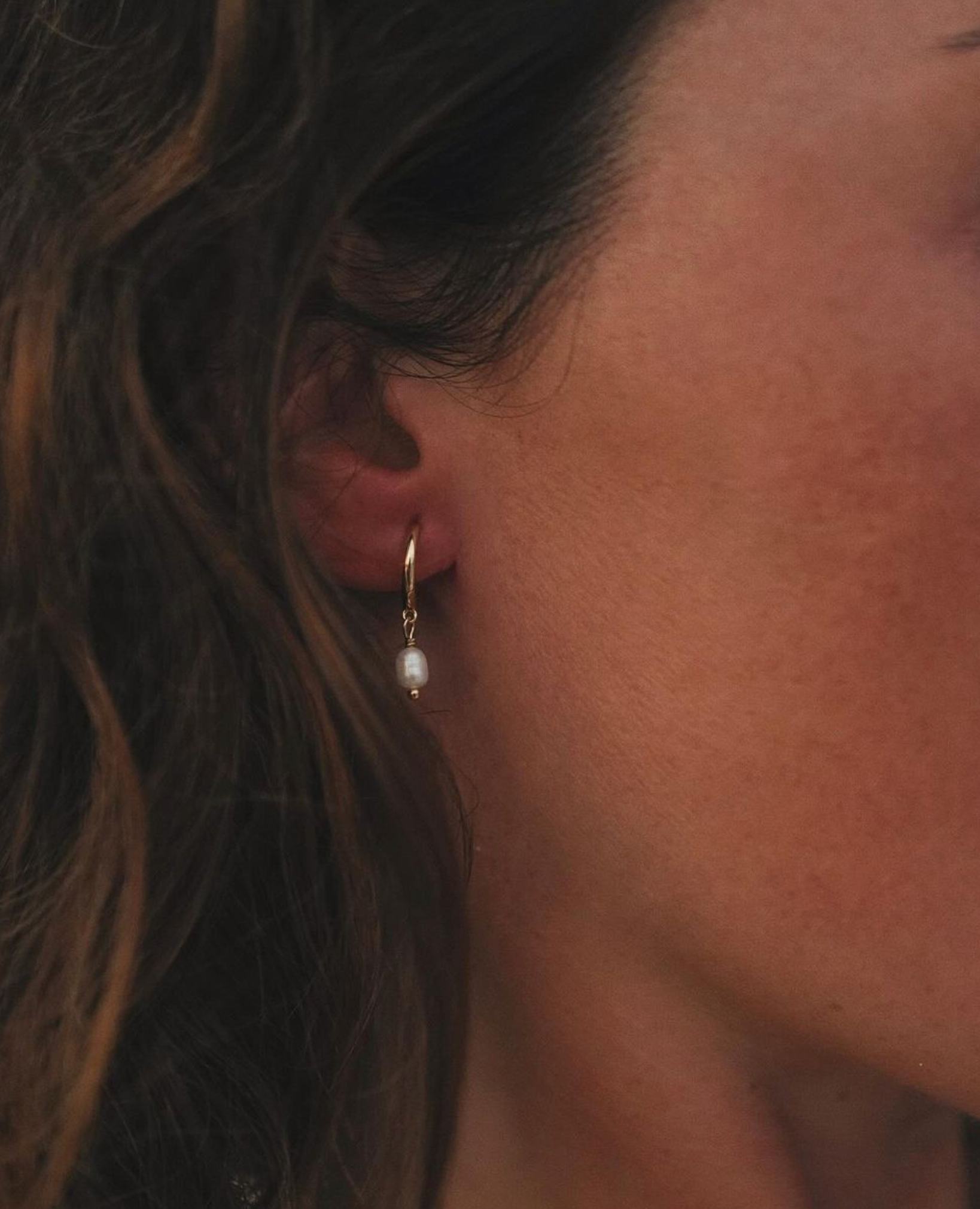 Model wearing the small size gold Pearl Hoops, highlighting the minimal pearl drop for an elegant, everyday look.