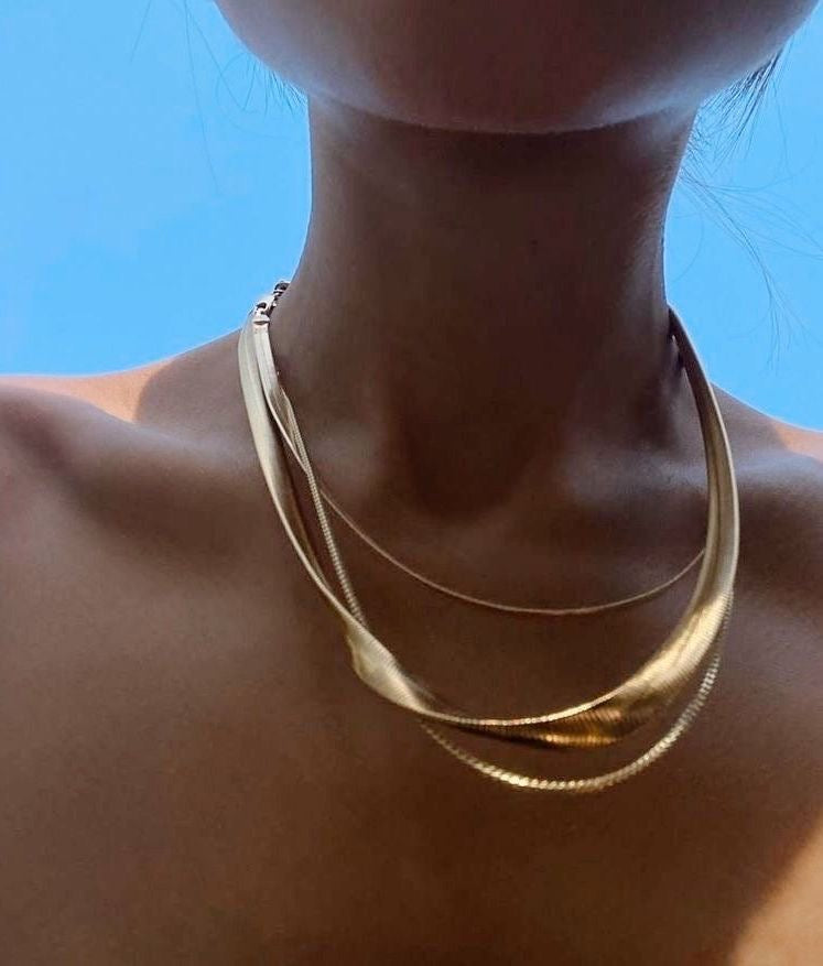 Gold necklace on a person against a blue sky background