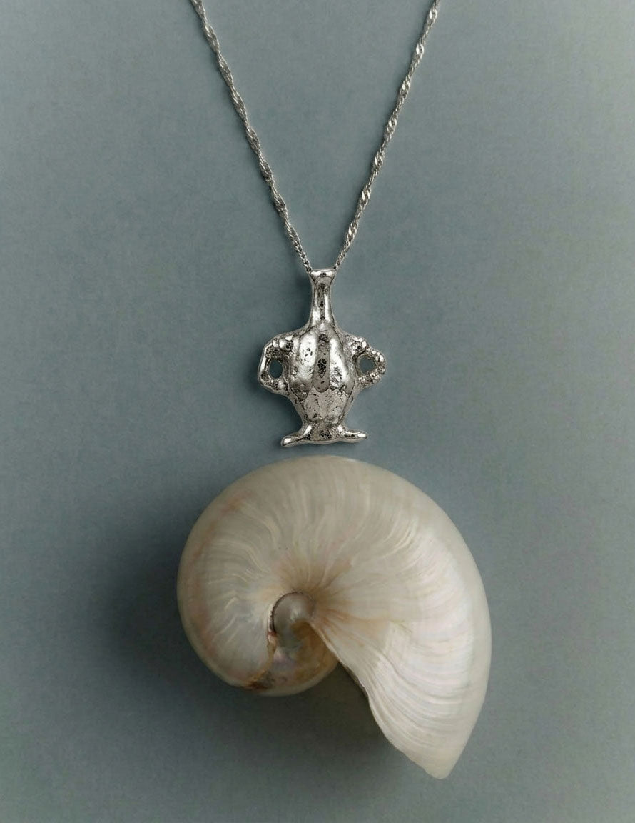 Shell pendant on a chain against a gray background