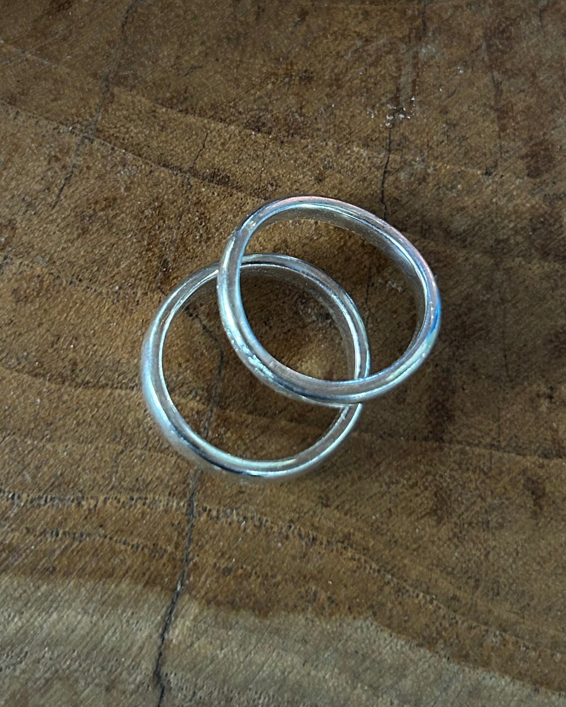 Two silver rings on a wooden surface