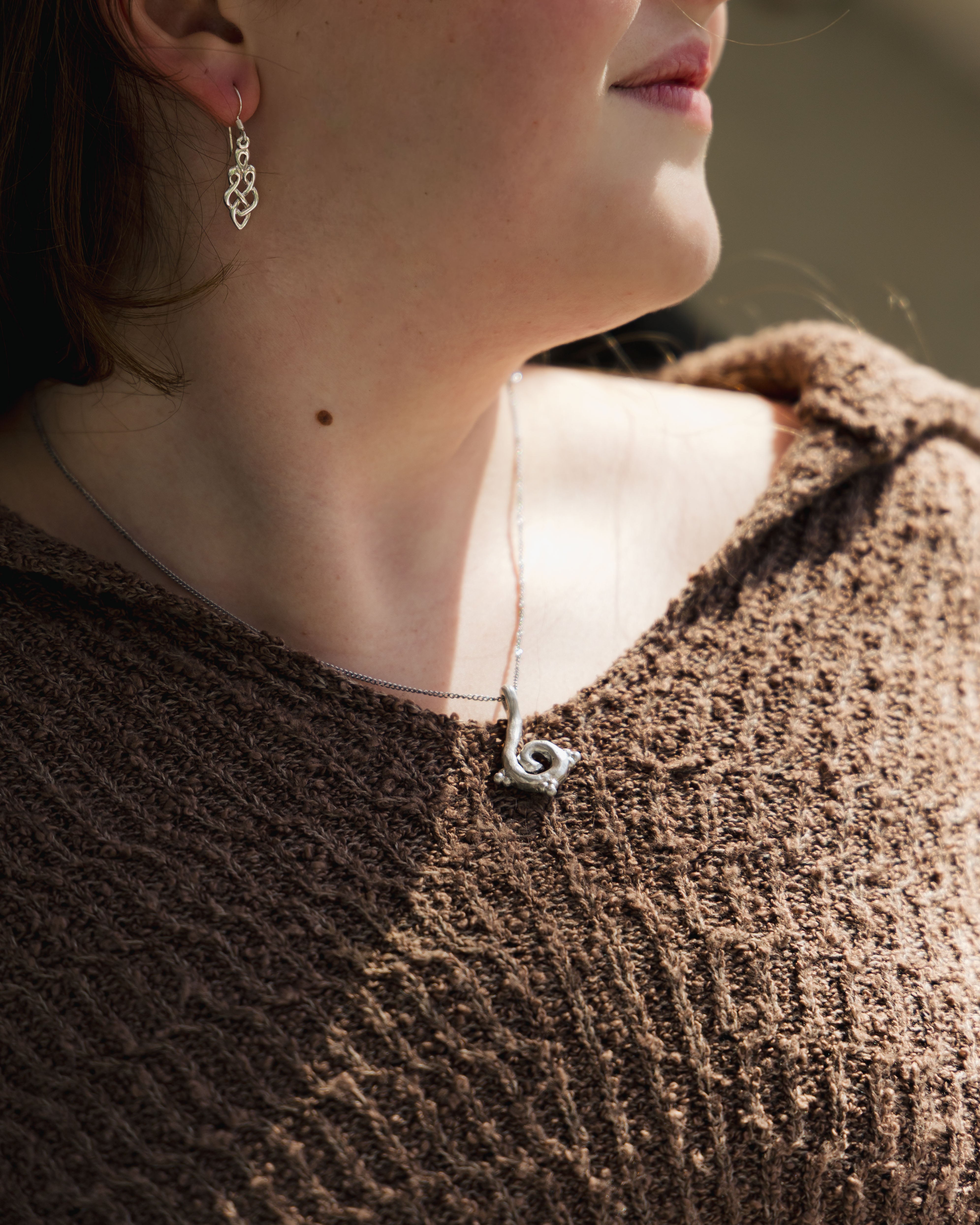 Close-up of a person wearing chunky silver swirl necklace