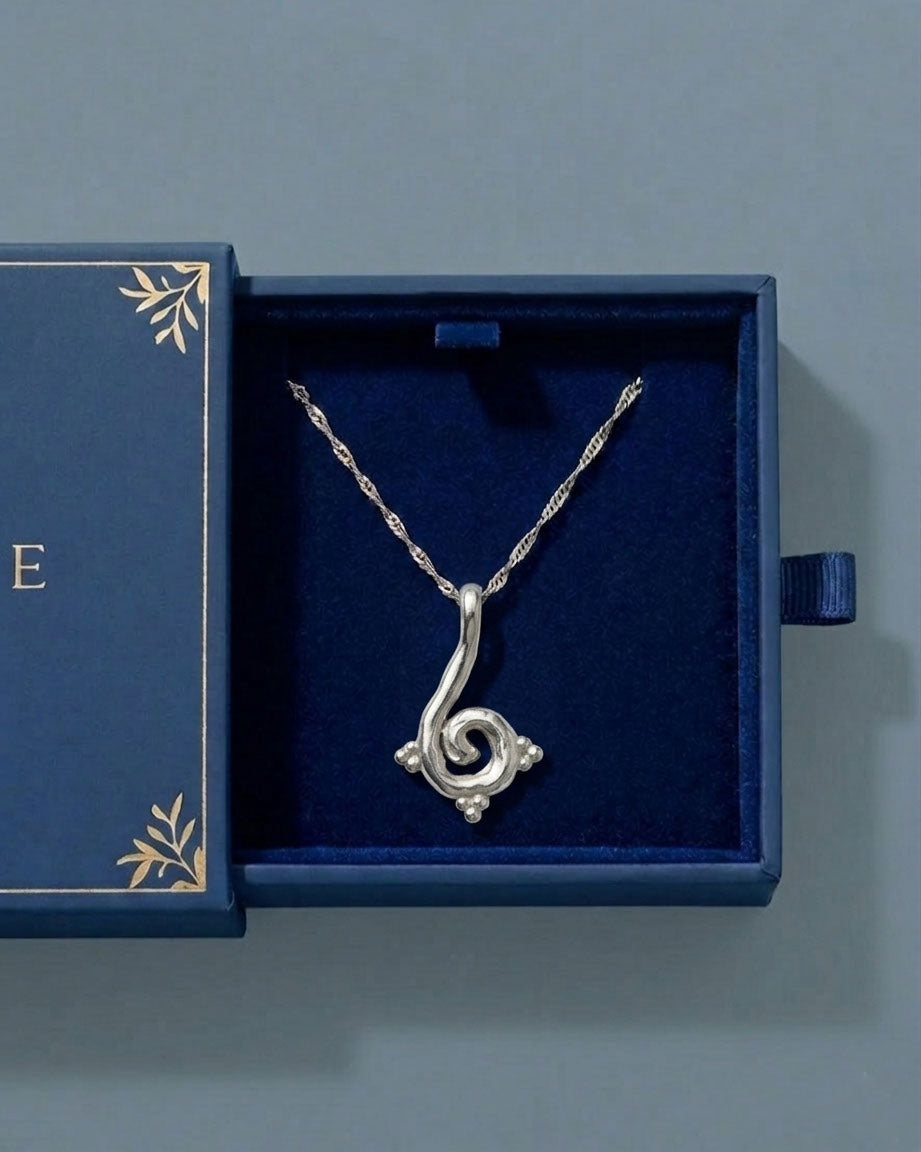 Silver necklace with a decorative pendant in a blue jewelry box.