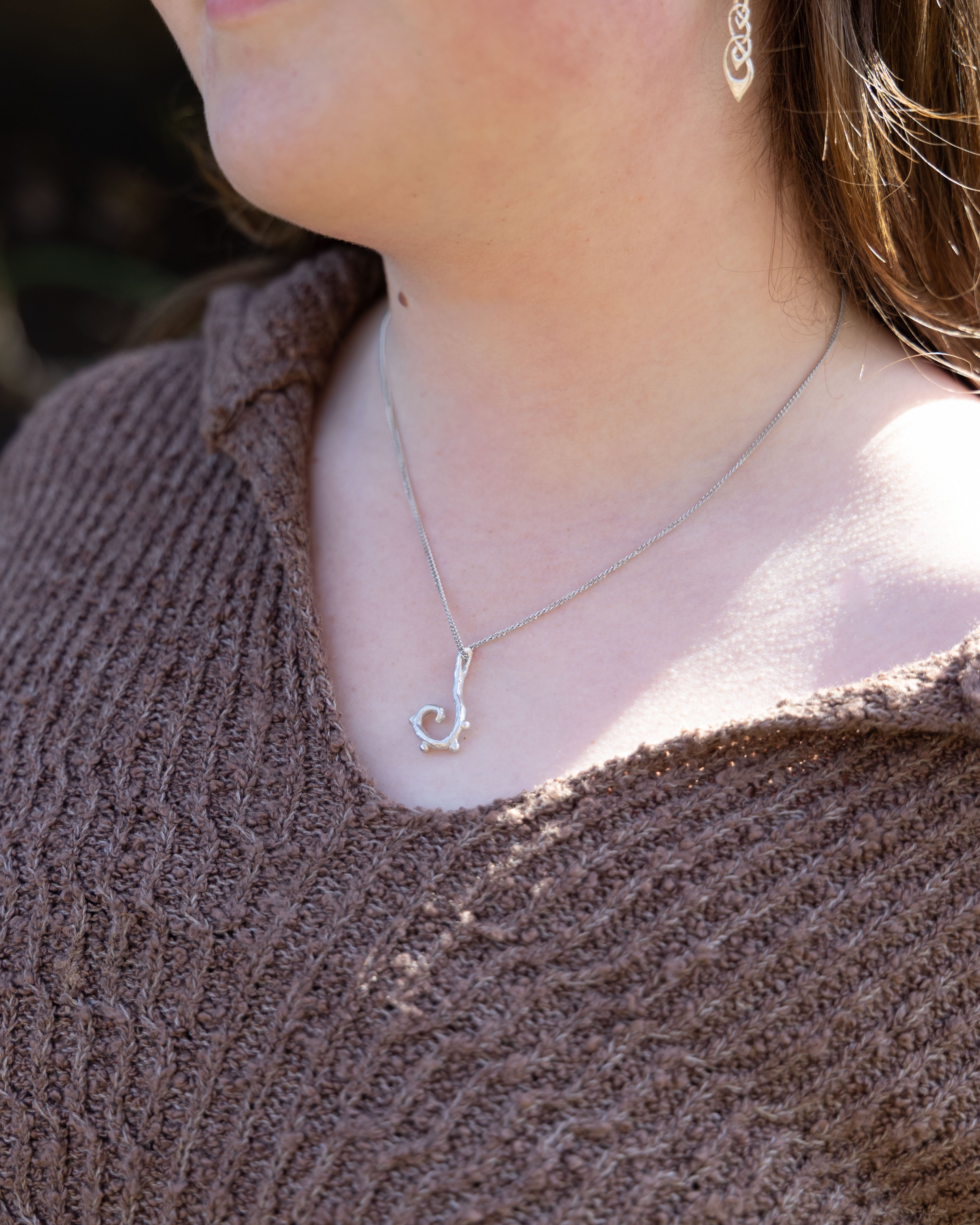 Close-up of a person wearing a delicate necklace with a heart pendant.