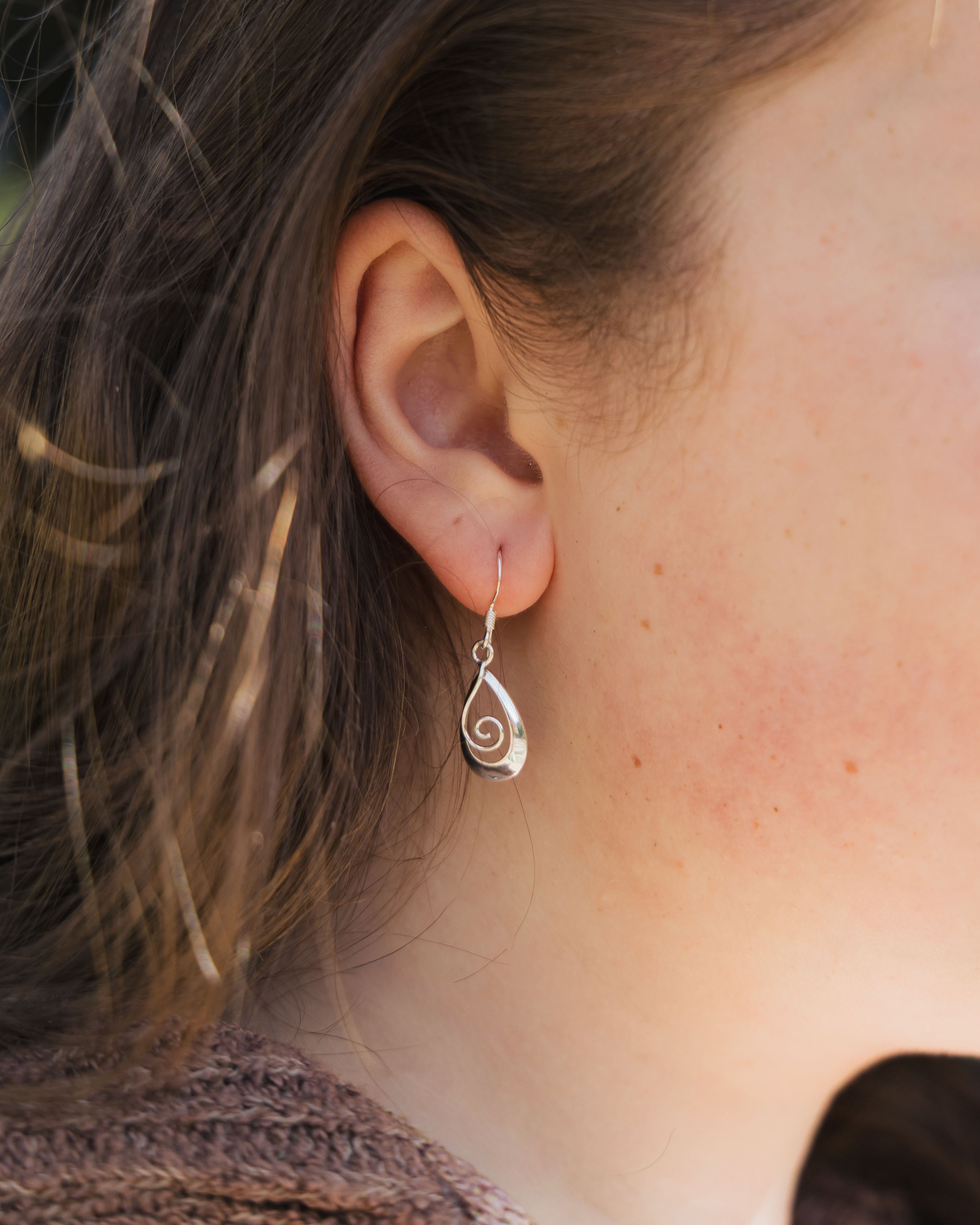 Close-up of a person wearing a silver spiral earring.