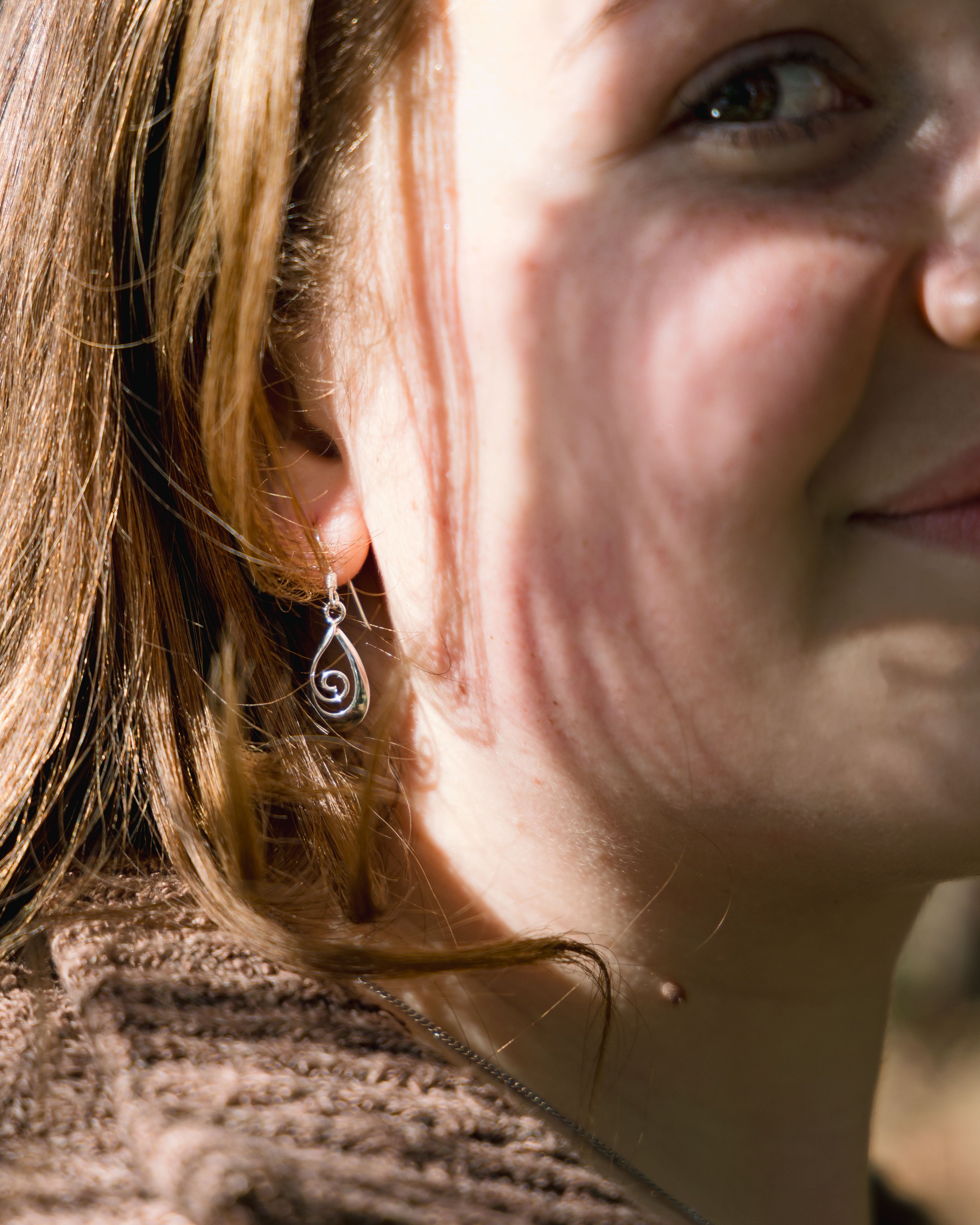 Close-up of a person with a spiral earring on their ear.
