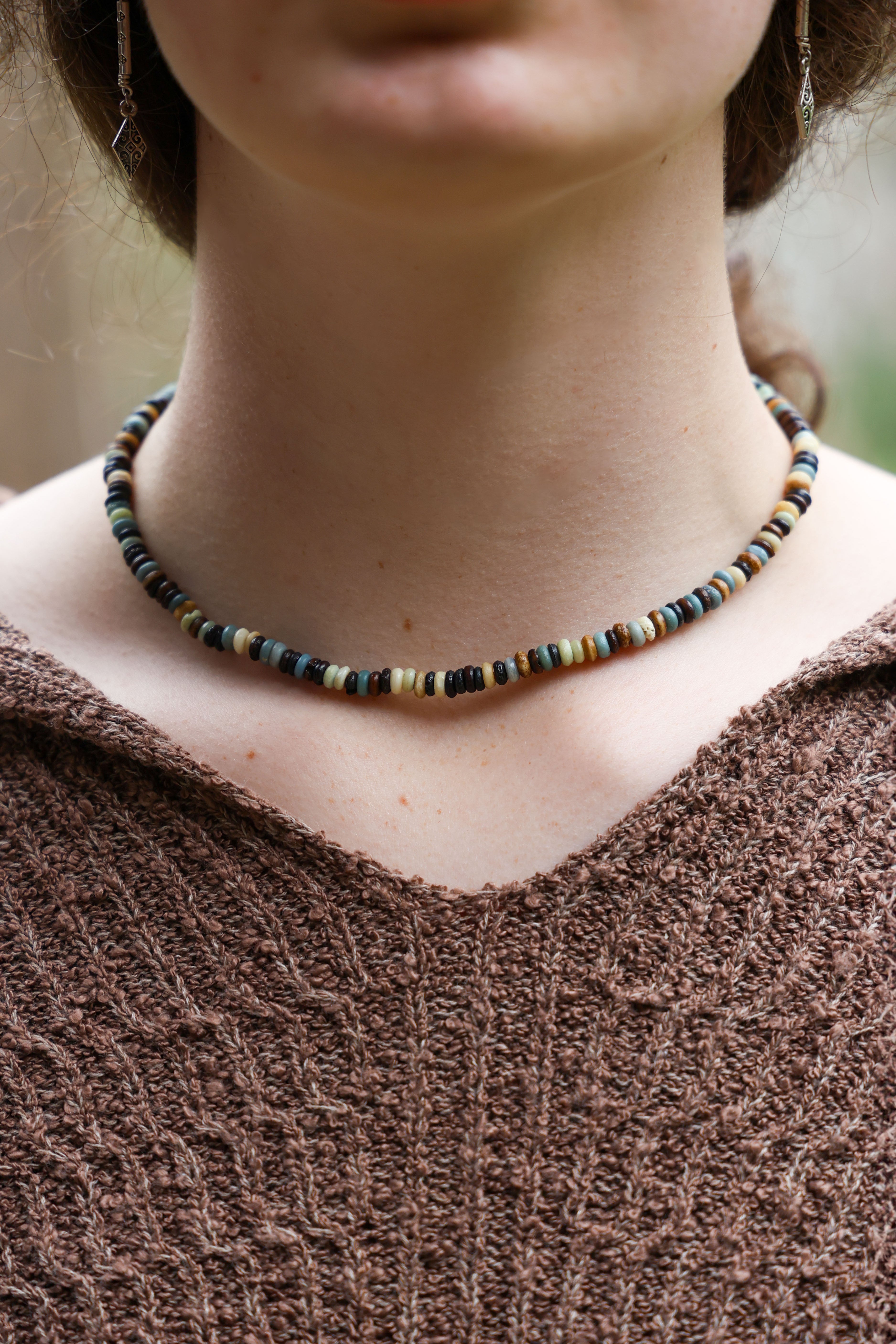 Close-up of a person wearing a colorful beaded bracelet on a textured surface.