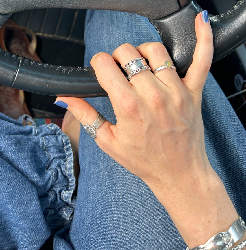 Hand wearing multiple handcrafted silver rings while driving, showcasing Yallambe jewellery stack.