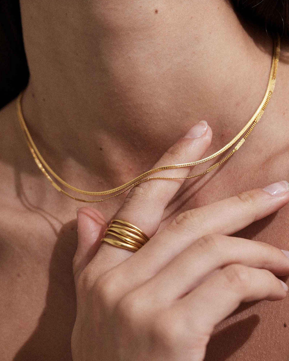 Close-up detail of Thin round Snake Chain Necklace on model, showing its seamless construction perfect for layering.