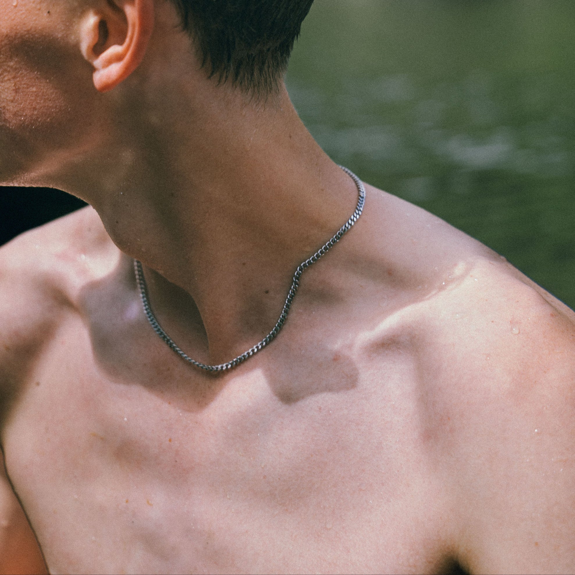Close-up of a person wearing necklace with a blurred natural background