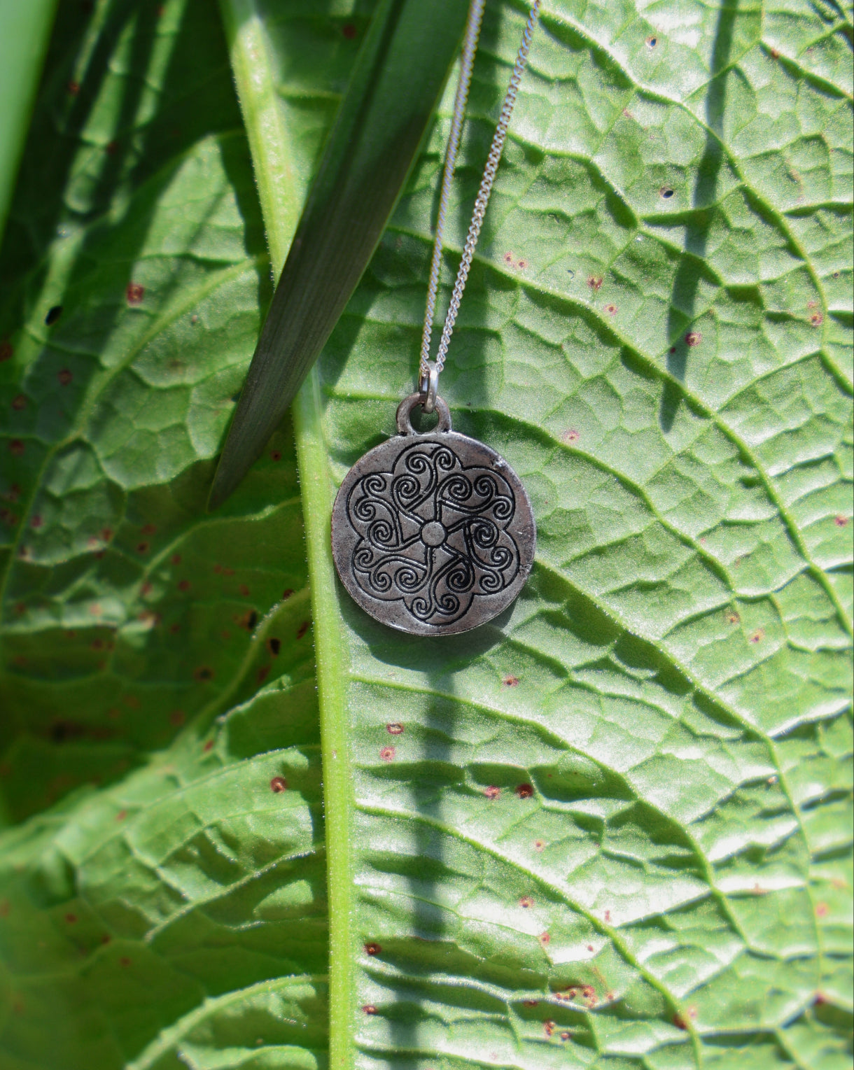 Necklace with a decorative pendant on a green leaf