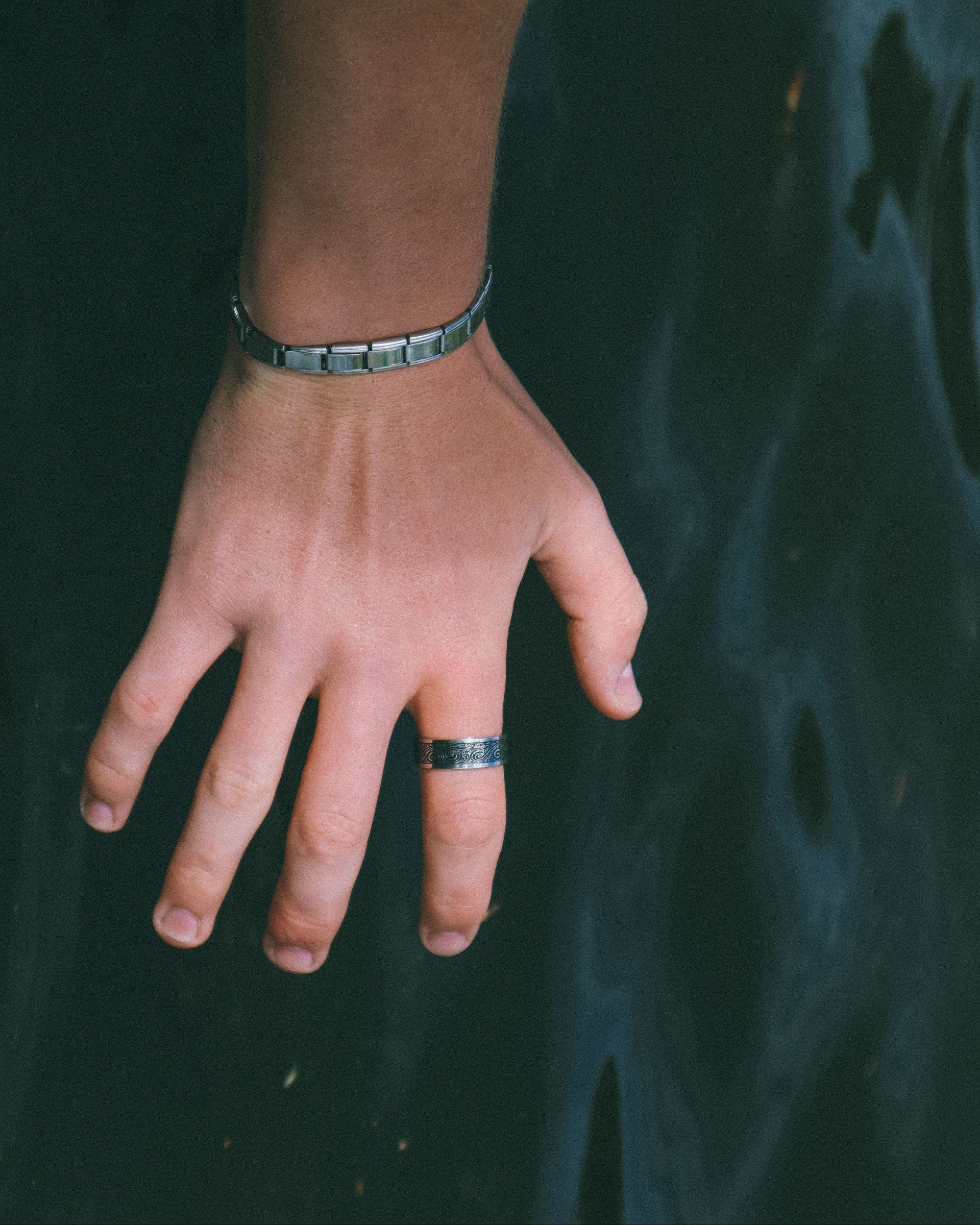 Hand with a ring and bracelet against a dark background