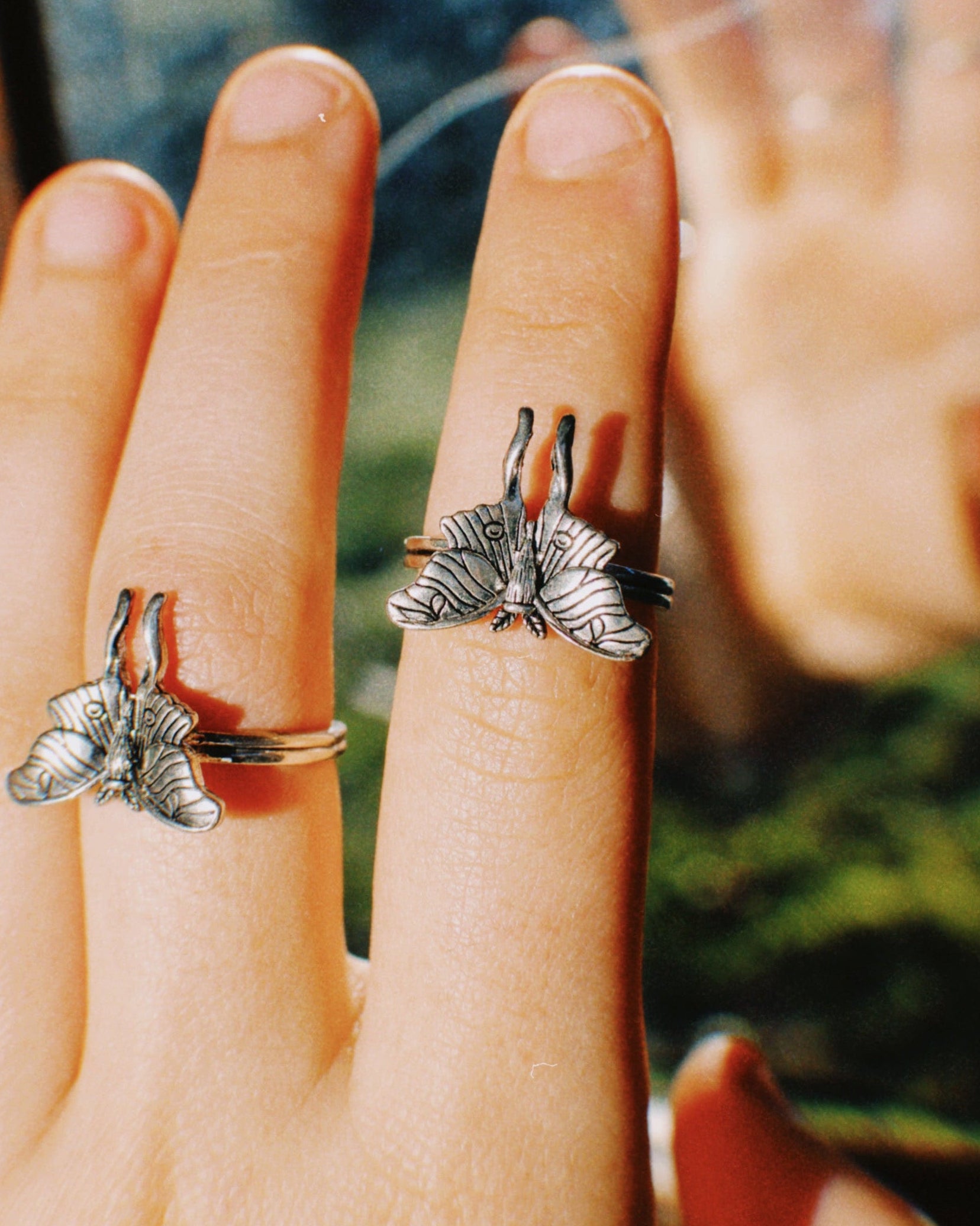 Silver butterfly ring on a hand with a blurred background