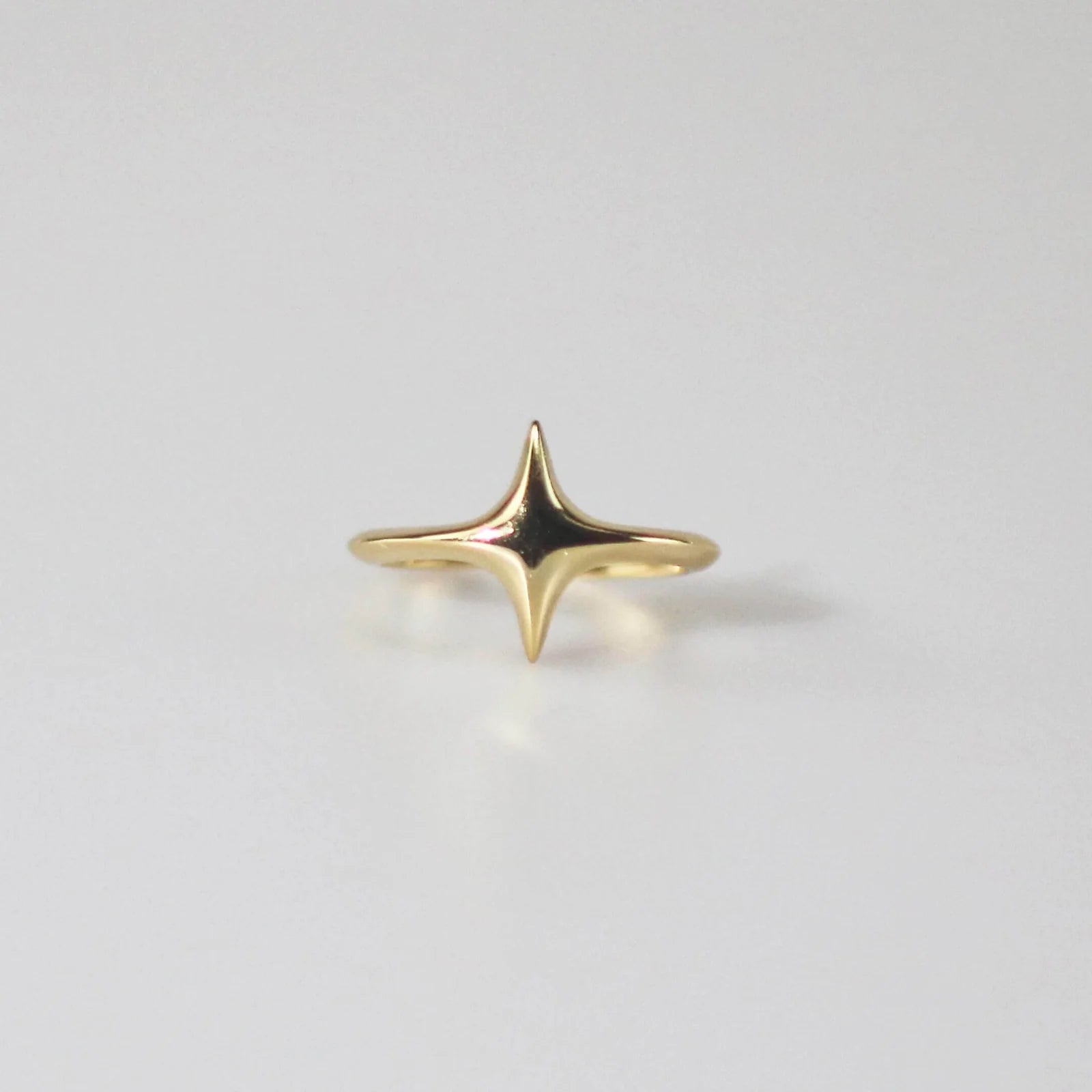 A gold-colored star-shaped ring on a white background.