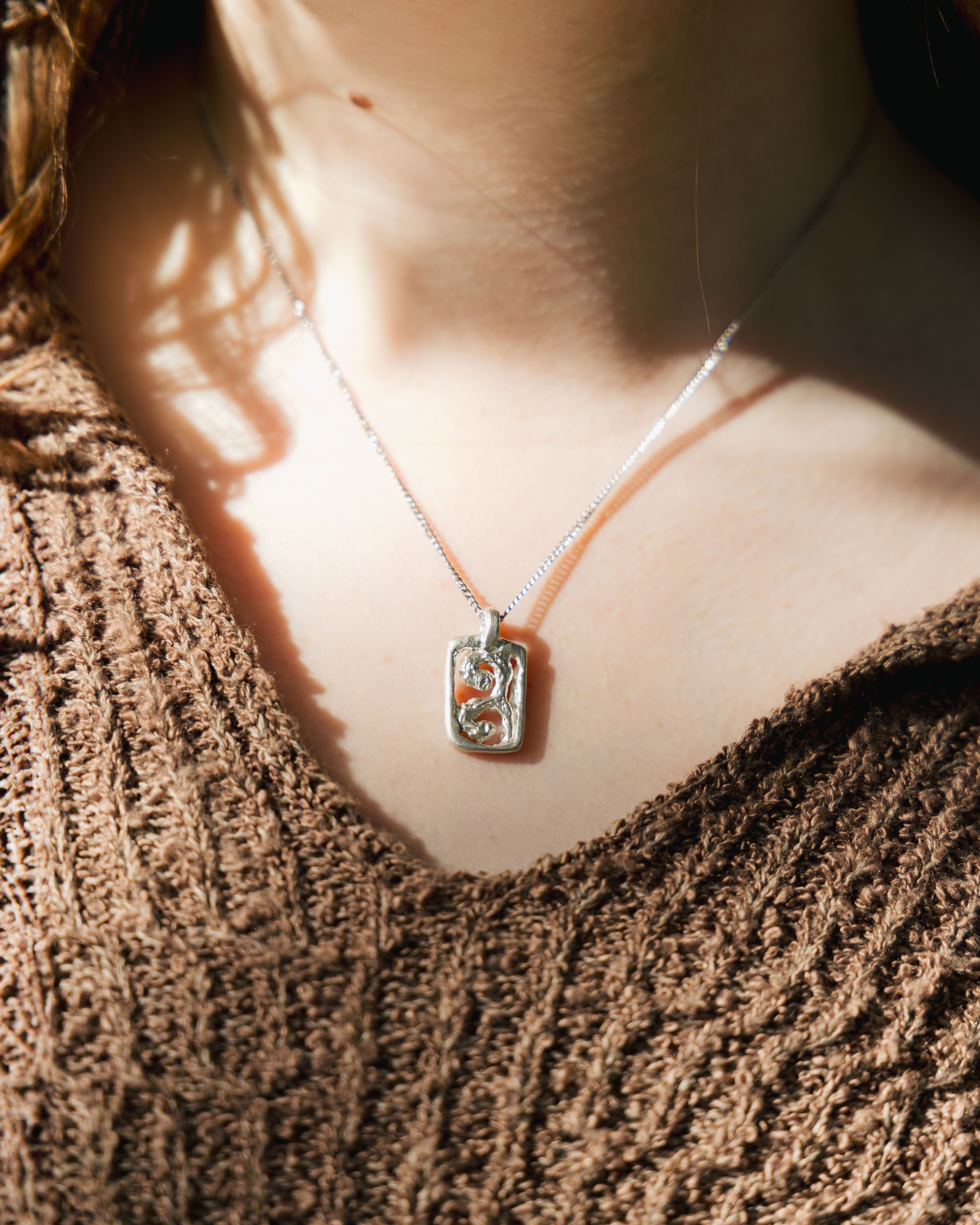 Close-up of a necklace with a pendant on a textured surface