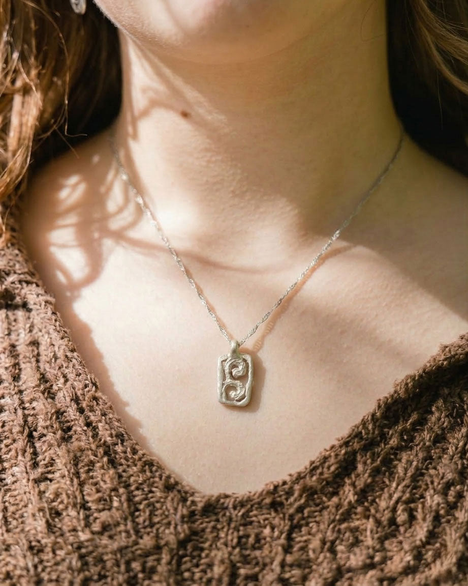 Necklace with a pendant worn by a person, with a soft focus on the background