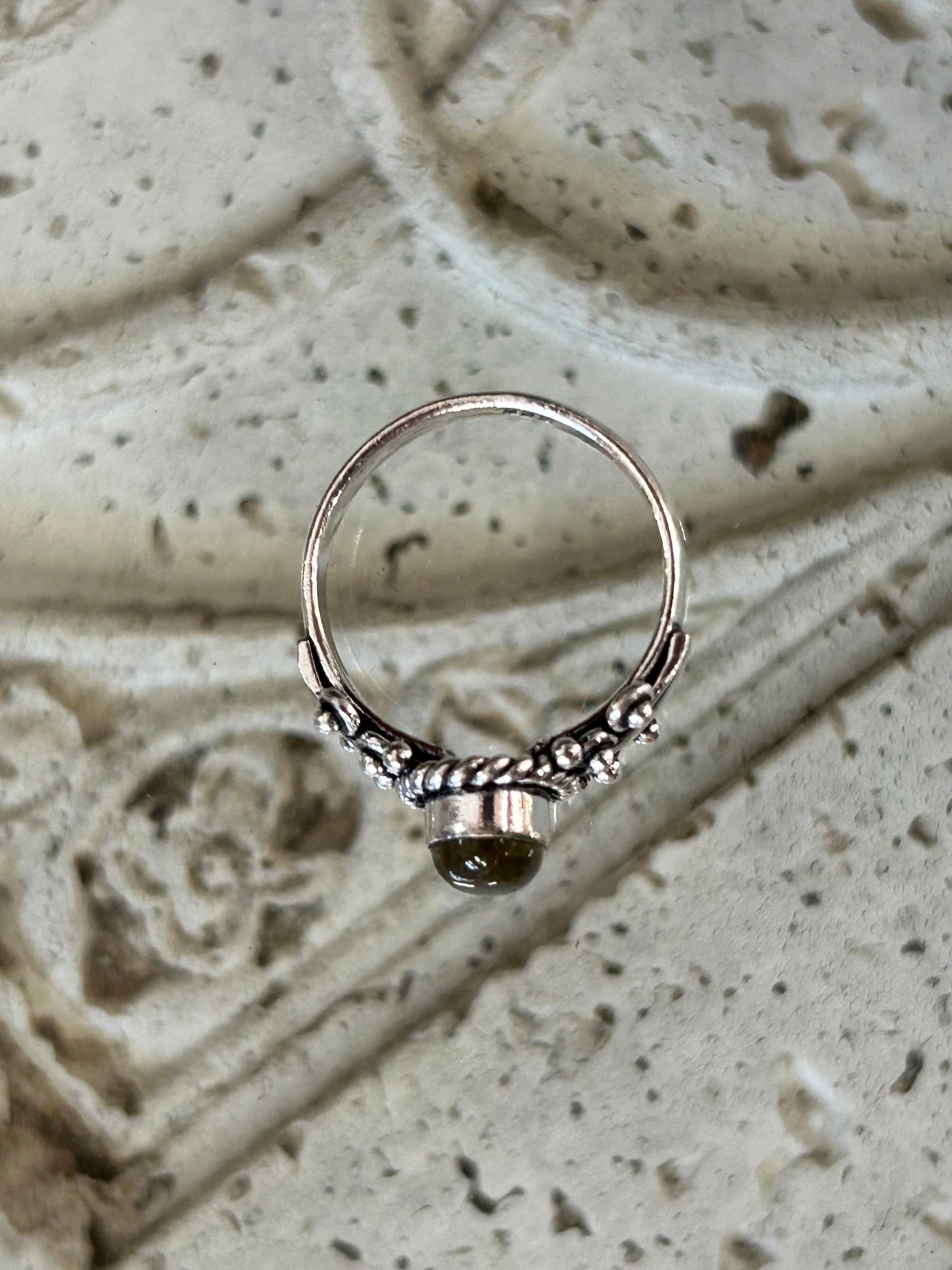 A silver ring with a labradorite stone, featuring intricate detailing 