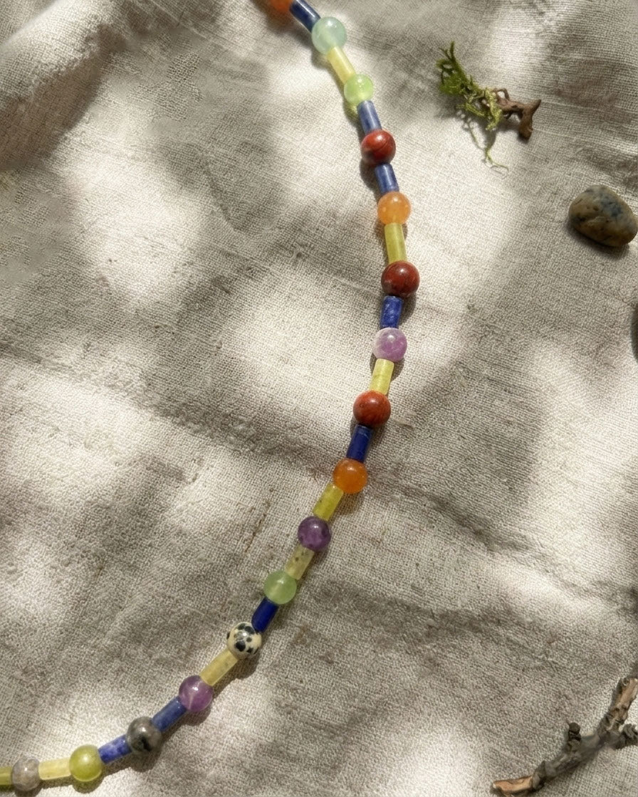 Colorful beaded necklace on a textured fabric background