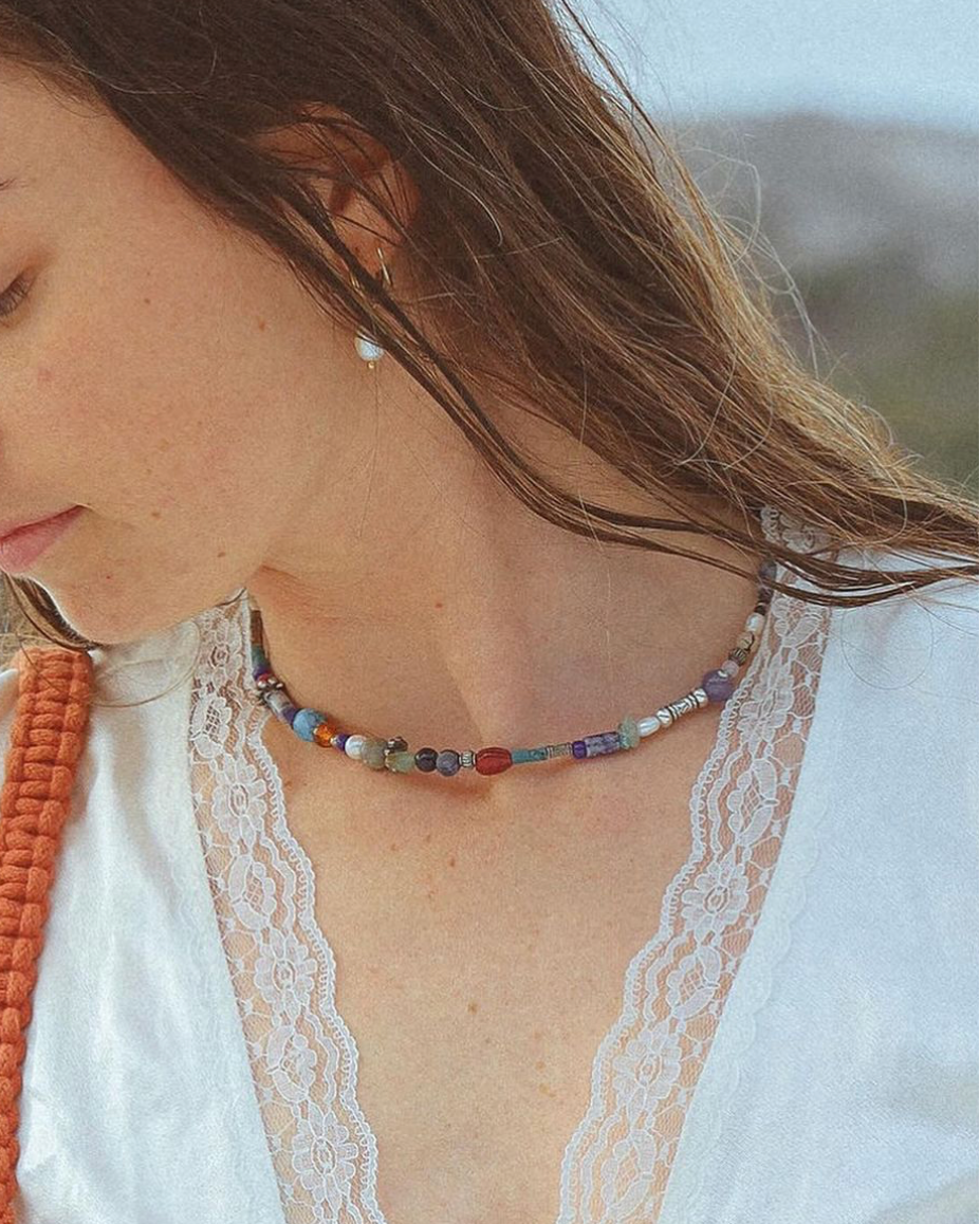 Woman wearing a beaded necklace with a blurred natural background