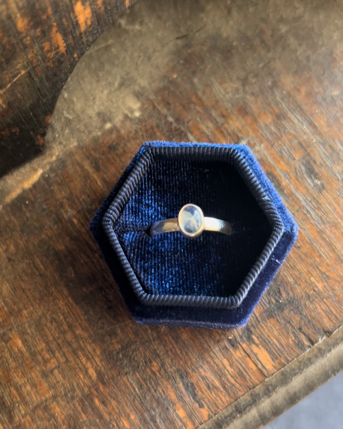 Ring in a blue velvet box on a wooden surface