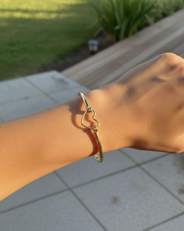 Gold bracelet on a wrist with heart closer 