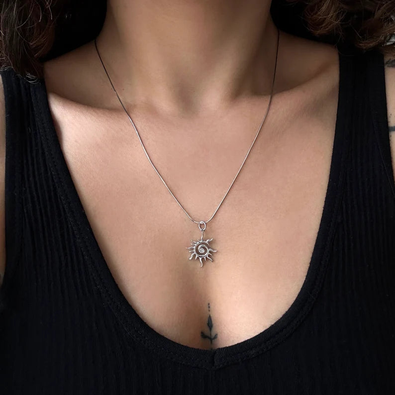 Silver sun and moon pendant necklace on a person wearing a black top.