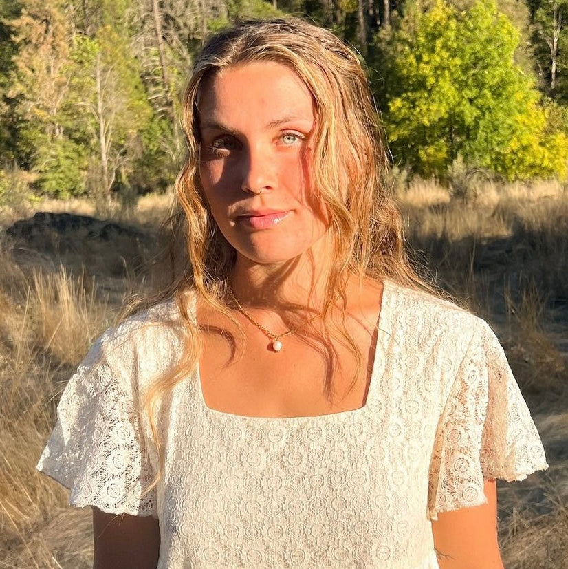model wearing the Classic Gold Pearl Necklace, showing the subtle single pearl drop pendant in sunlight.
